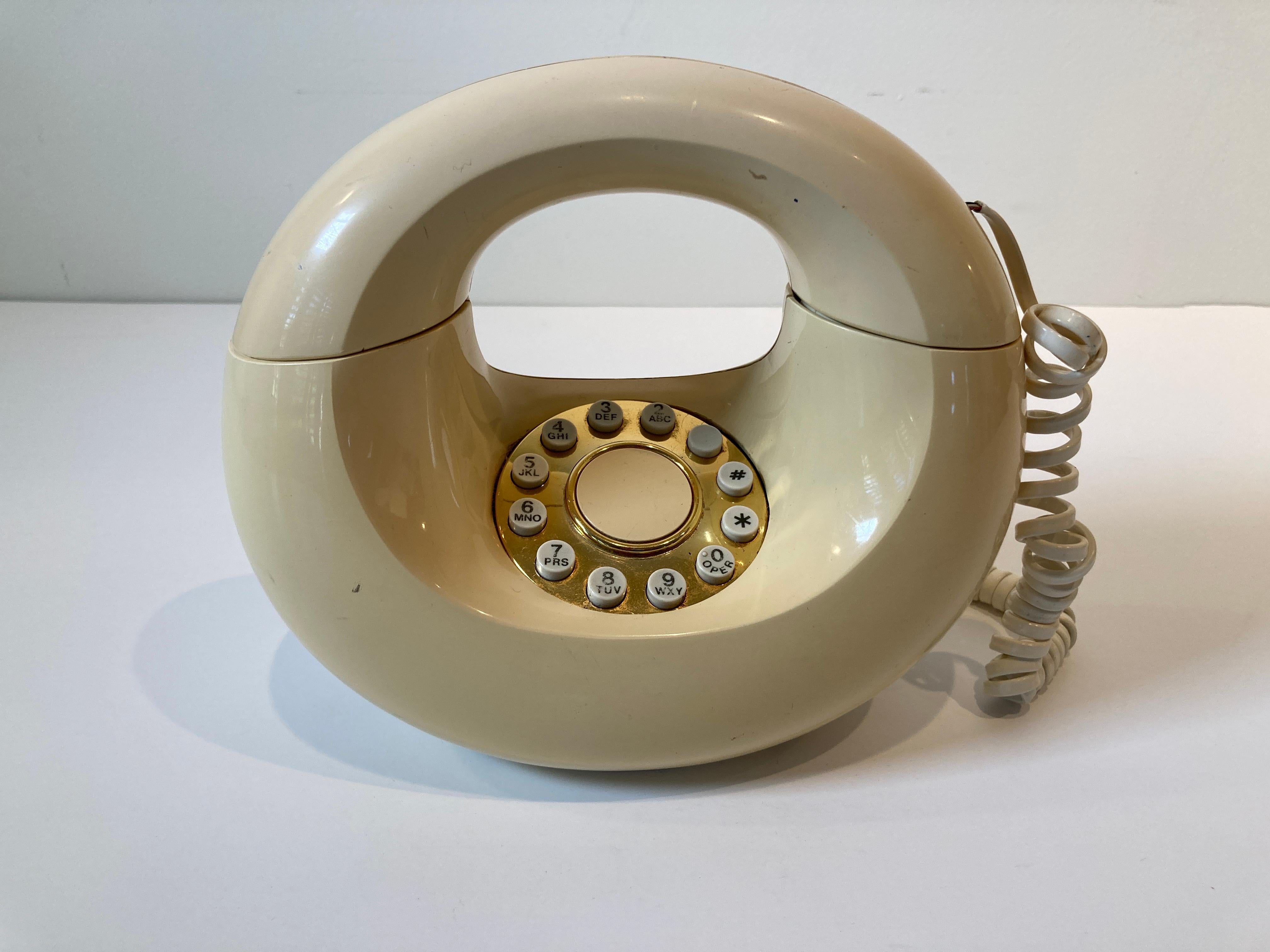 Vintage 1970s white vanilla color Western Electric sculptura Donut touch phone.
Western electric Sculptura Donut / Handbag phone in good condition.
Vintage Genie push button telephone in cream color, Donut shape RETRO Modern style telephone.
Due to