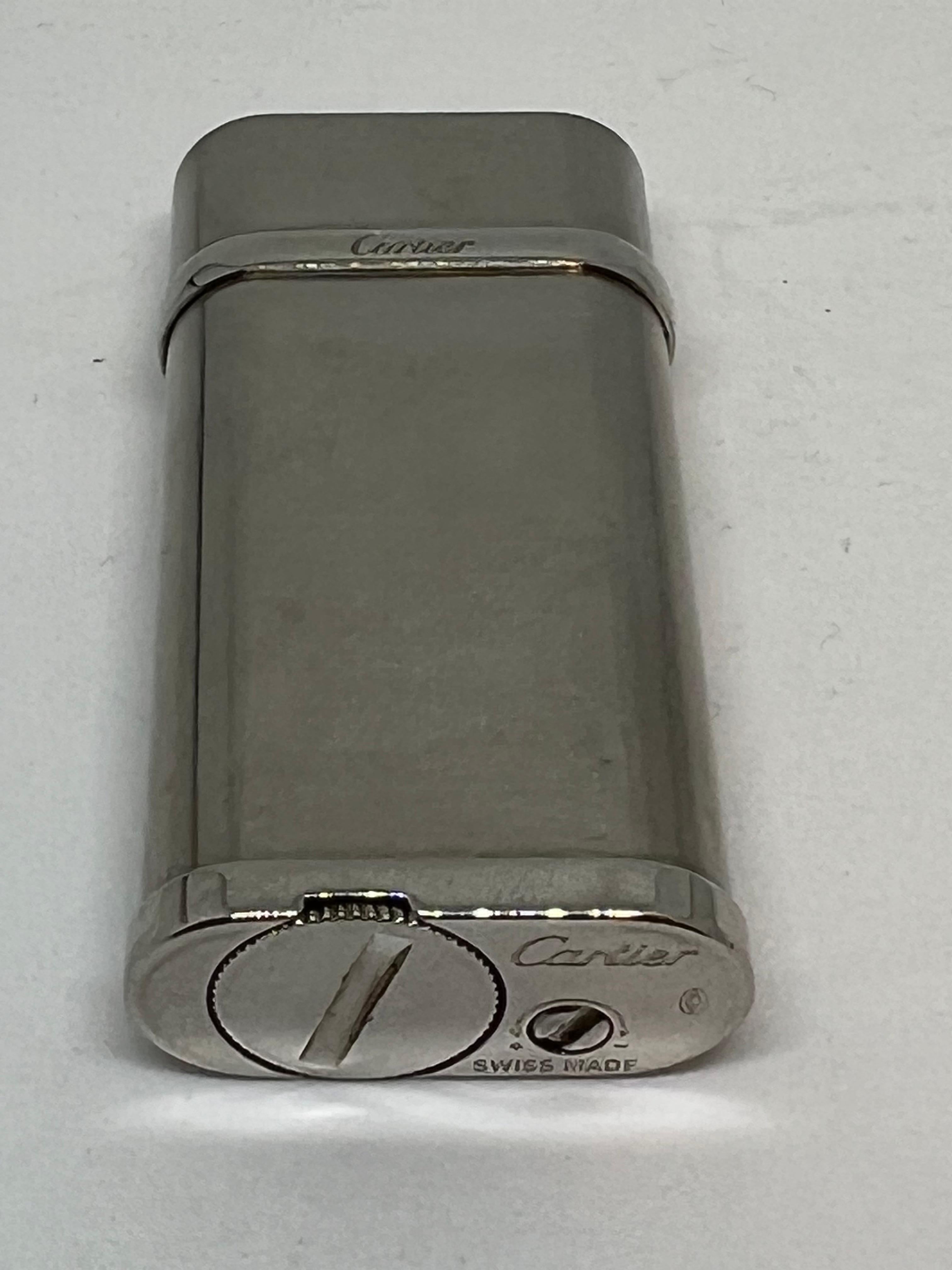 Retro Silver and Platinum finish Cartier lighter 
The lighter comes in its original Cartier box with papers and certificate
In mint working condition, the lighter sparks, ignites and flames 
It’s even has it outsize Cartier cover box 
Circa 1980s