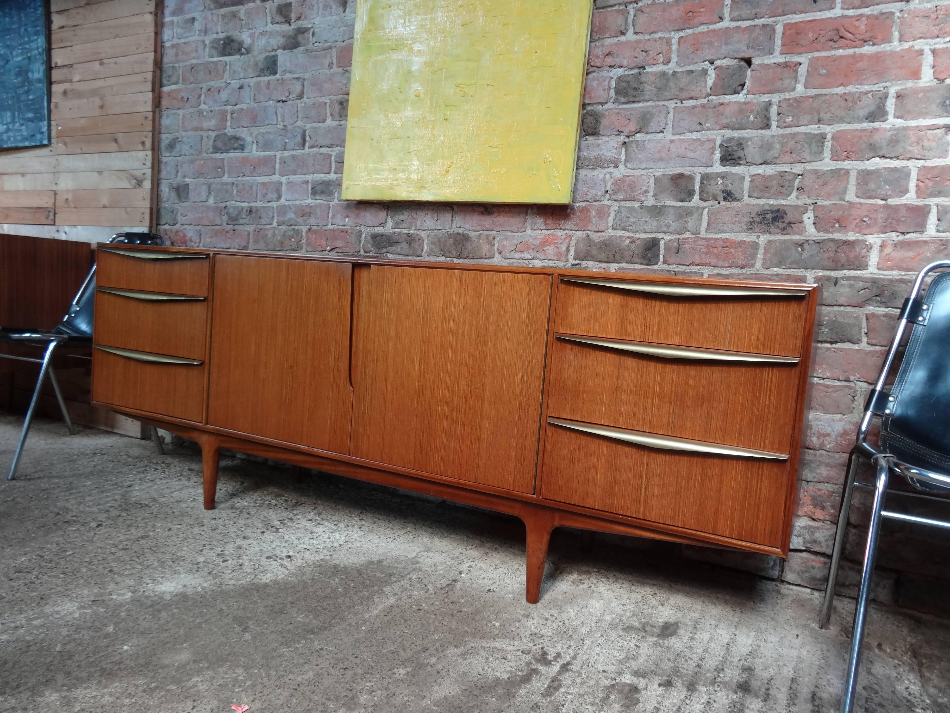 Most sought after vintage 1960s Mcintosh sideboard by Tom Robertson. It has three drawers with brass pull handles, cupboard space, and a drinks section with a useful pullout shelf. Credenza is in very good original condition. I have only seen two