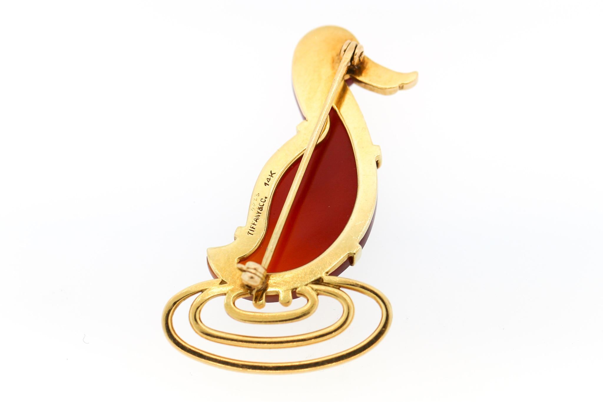 A vintage 14k yellow gold carnelian duck pin by Tiffany & Co., circa 1940. This whimsical duck is shown standing in water, and the body of the duck is carved amber colored carnelian. The pin is delightful and well executed. It is 1.75 inches tall.