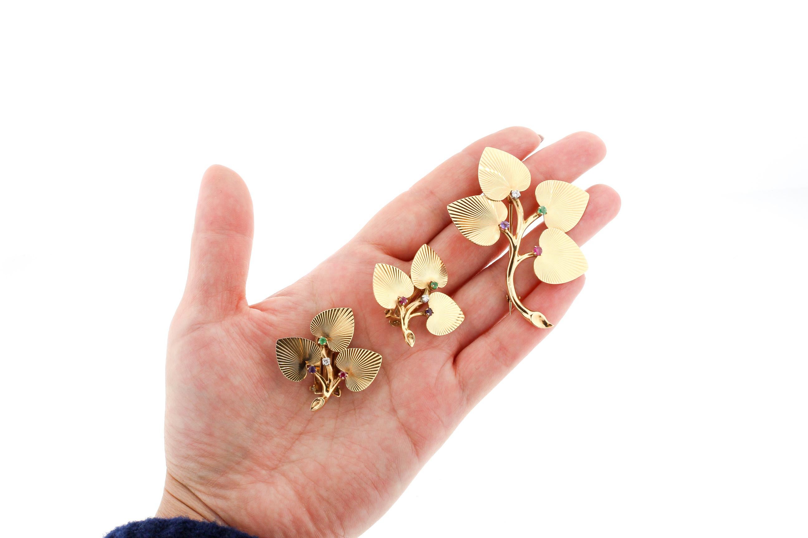 A lovely Retro set of 14k gold leaf earrings with matching pin made by Tiffany & Co. around the 1940s. The textured heart shaped leaves make a cluster set with a small Diamond, Emerald, Amethyst and Emerald. Spelling DEAR. The matching pin has the
