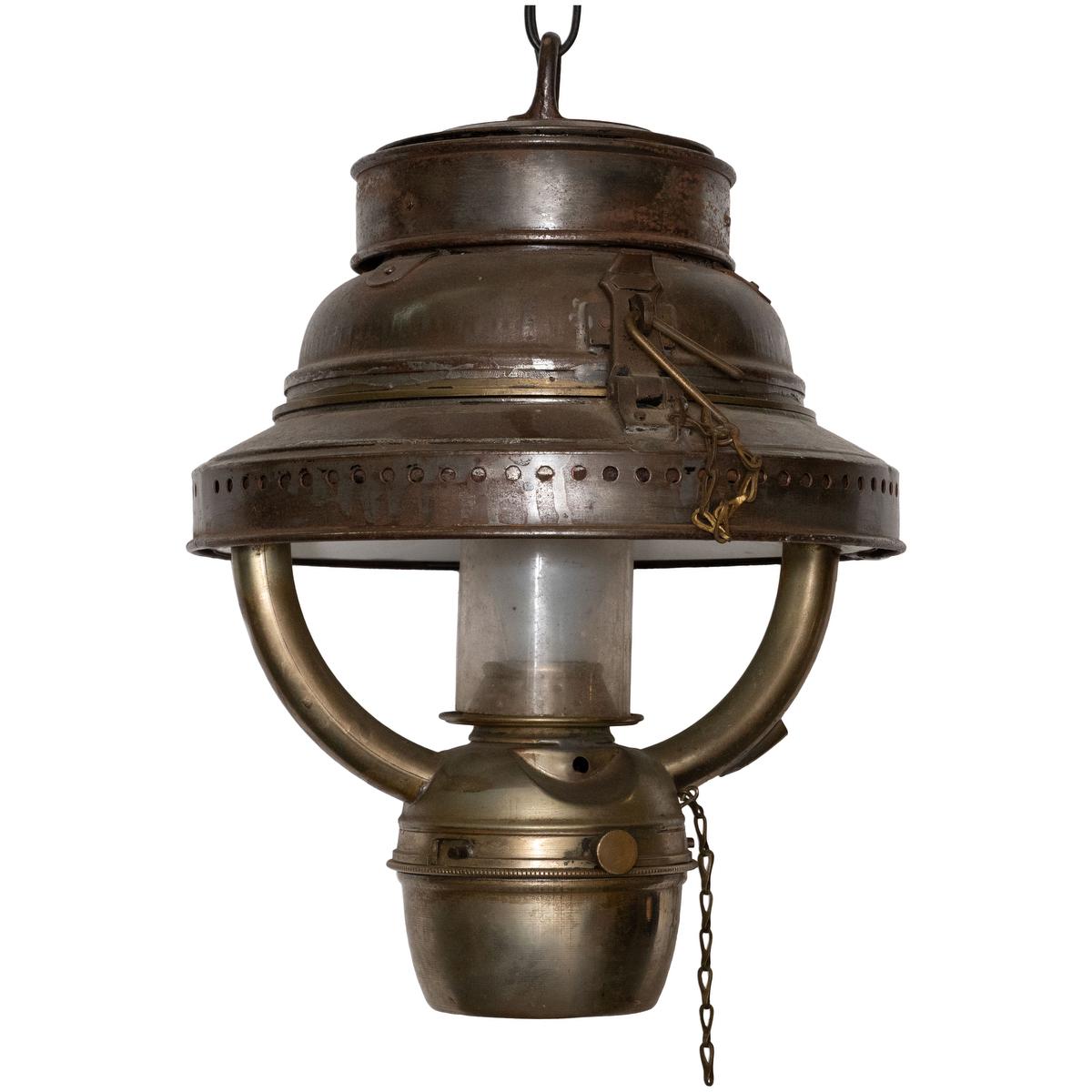 Vintage metal kerosene lantern with central glass shade retrofitted for electrified home use.