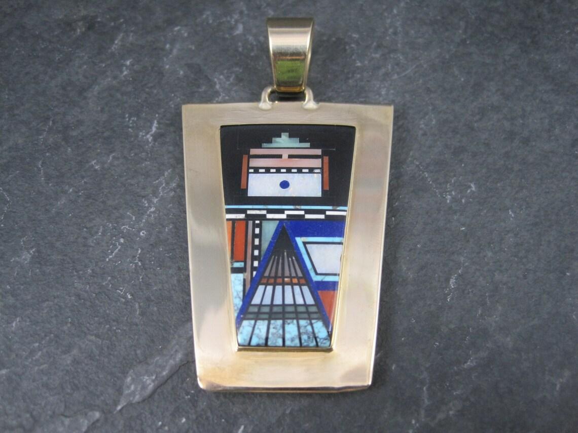 This stunning reversible pendant is 14k yellow gold.
It is the creation of Navajo Jerry Nelson.

It features inlay in jet, coral, spiny oyster, turquoise, lapis lazuli, opal, white turquoise and more.

Measurements: 1 1/2, 2 5/8 inches
Weight: 24.4