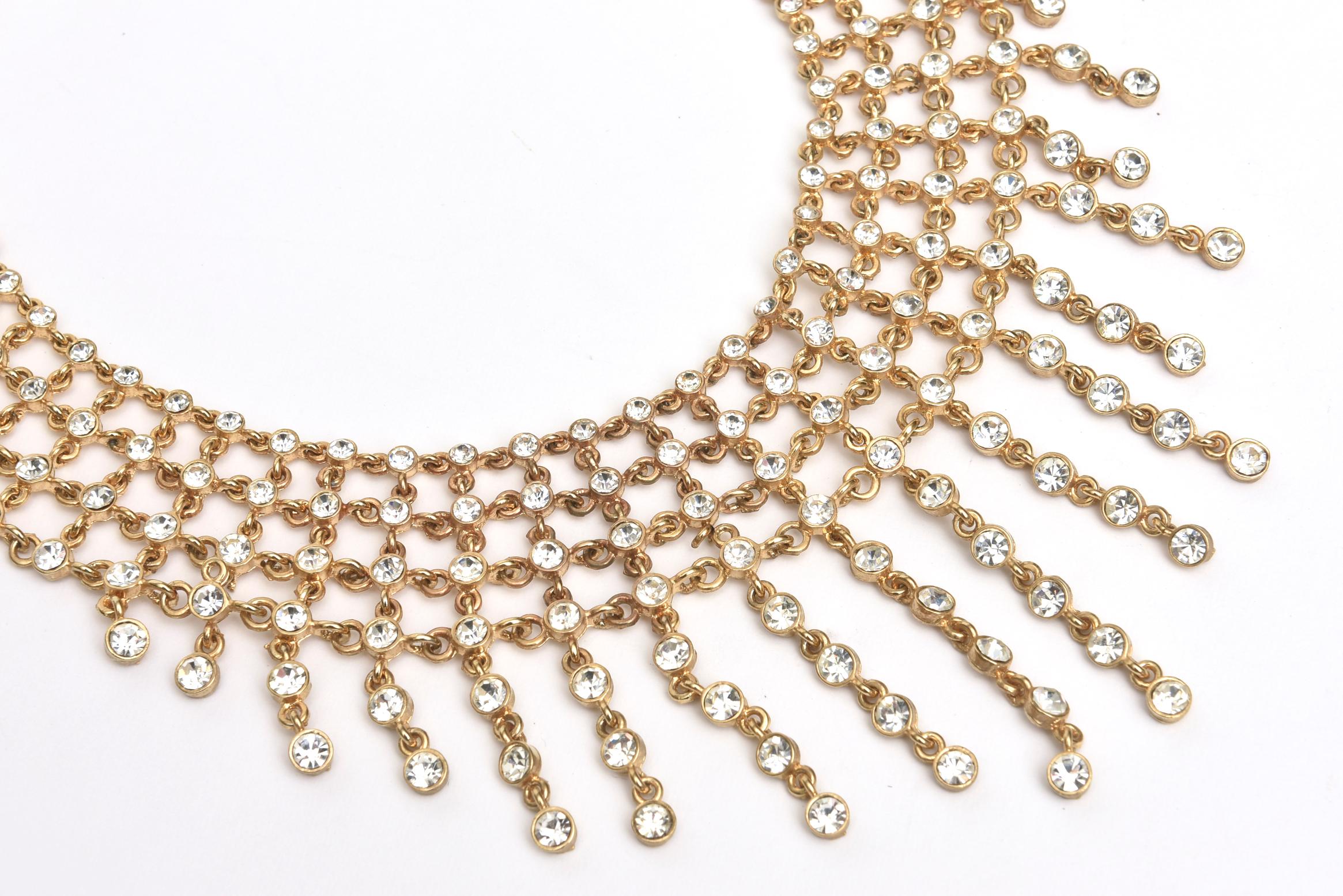 This stunning and elegant cascading bib necklace is filled of 4 tiers of rhinestones set in folded metal with hanging stands of the same at the bottom. They are different lengths. You can make it longer or shorter on the neck as there are approx 8