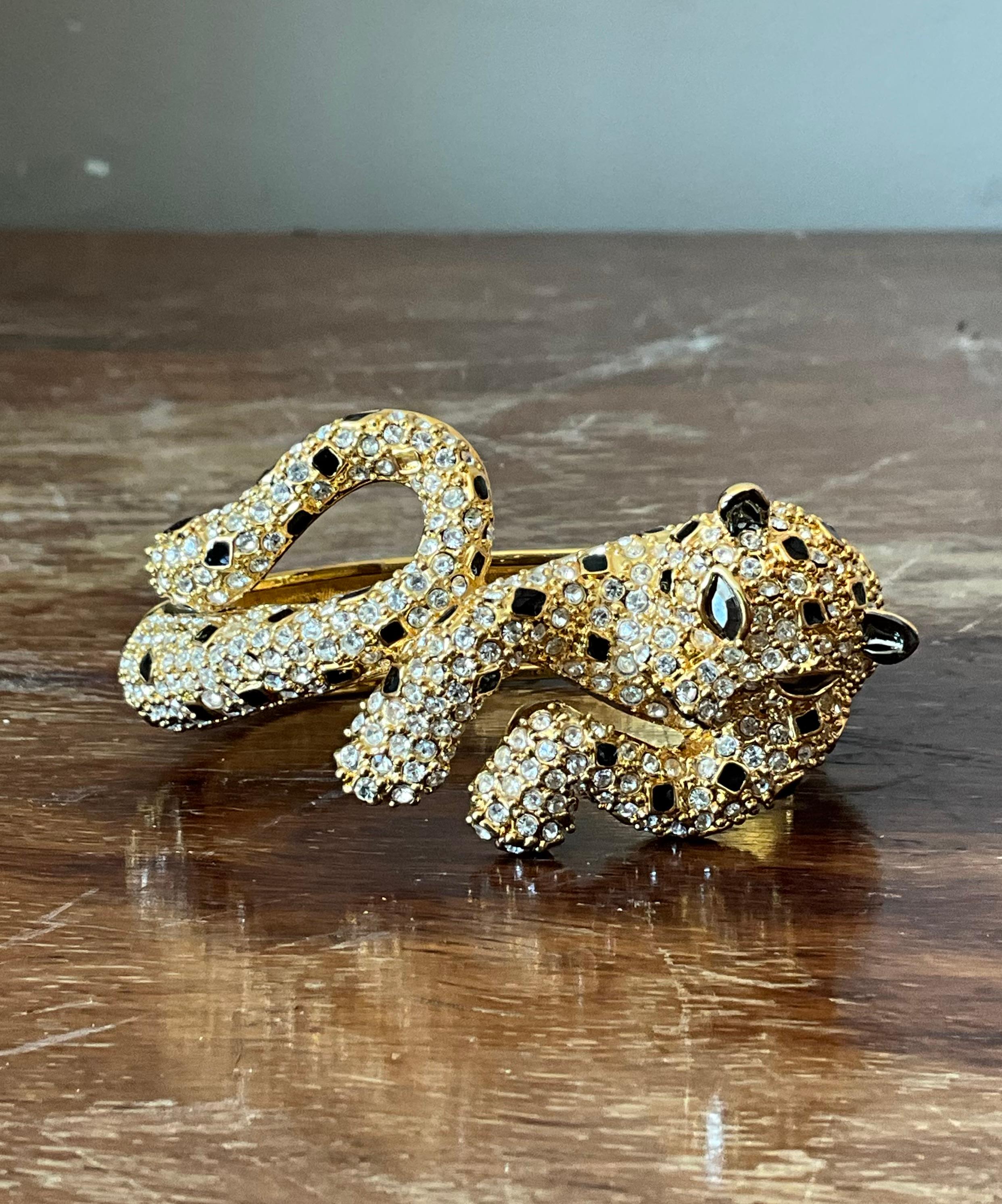 Unleash your wild side with this striking Vintage Rhinestone & Black Enamel Leopard Bracelet. This bold statement piece features a sleek, sculpted leopard design, adorned with glistening clear rhinestones that accentuate its graceful form. Rich