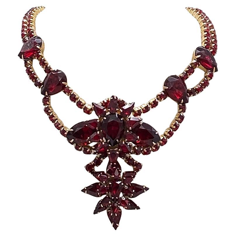 This is a luxurious blood red rhinestone necklace. There are  peardrop, teardrop, square and round shaped rhinestones composing this double strand with pendant necklace. All prong set rhinestones on copper metal back. It has two enhanced ring