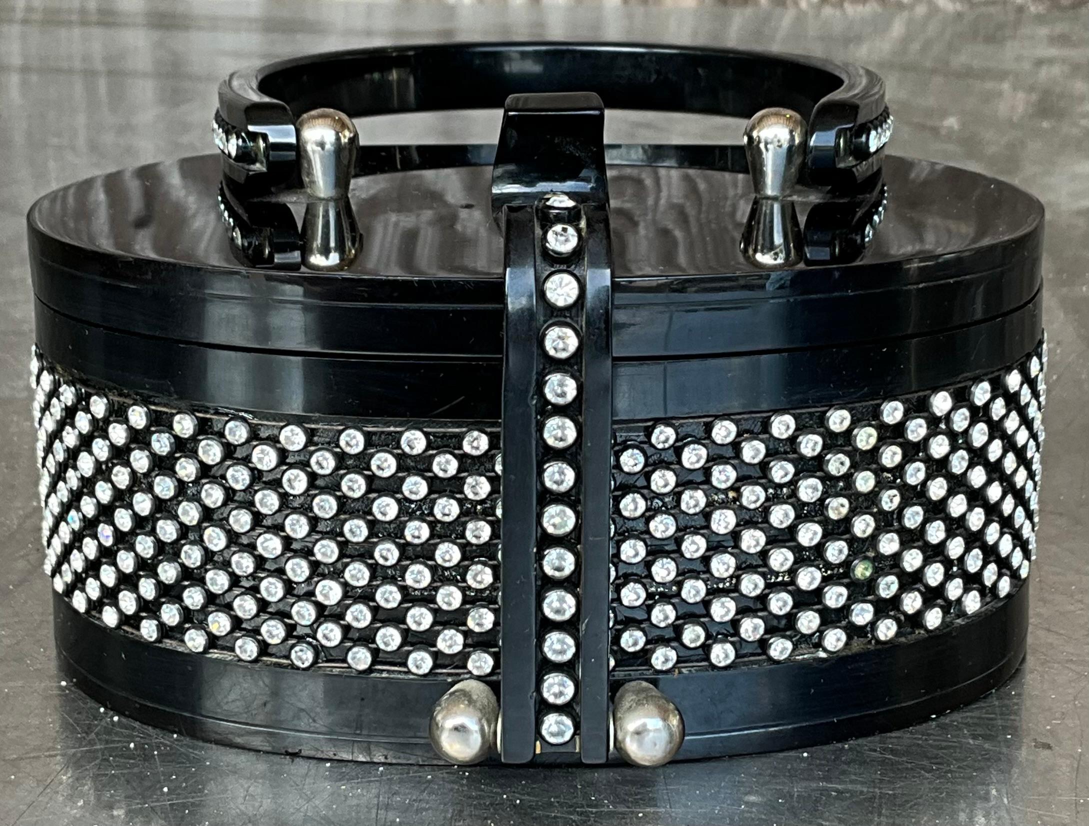 Add a touch of vintage elegance to your collection with this stunning rhinestone-embellished Lucite purse, designed in the iconic style of Wilardy. This mid-century treasure features a sleek, sculptural silhouette crafted from translucent Lucite,