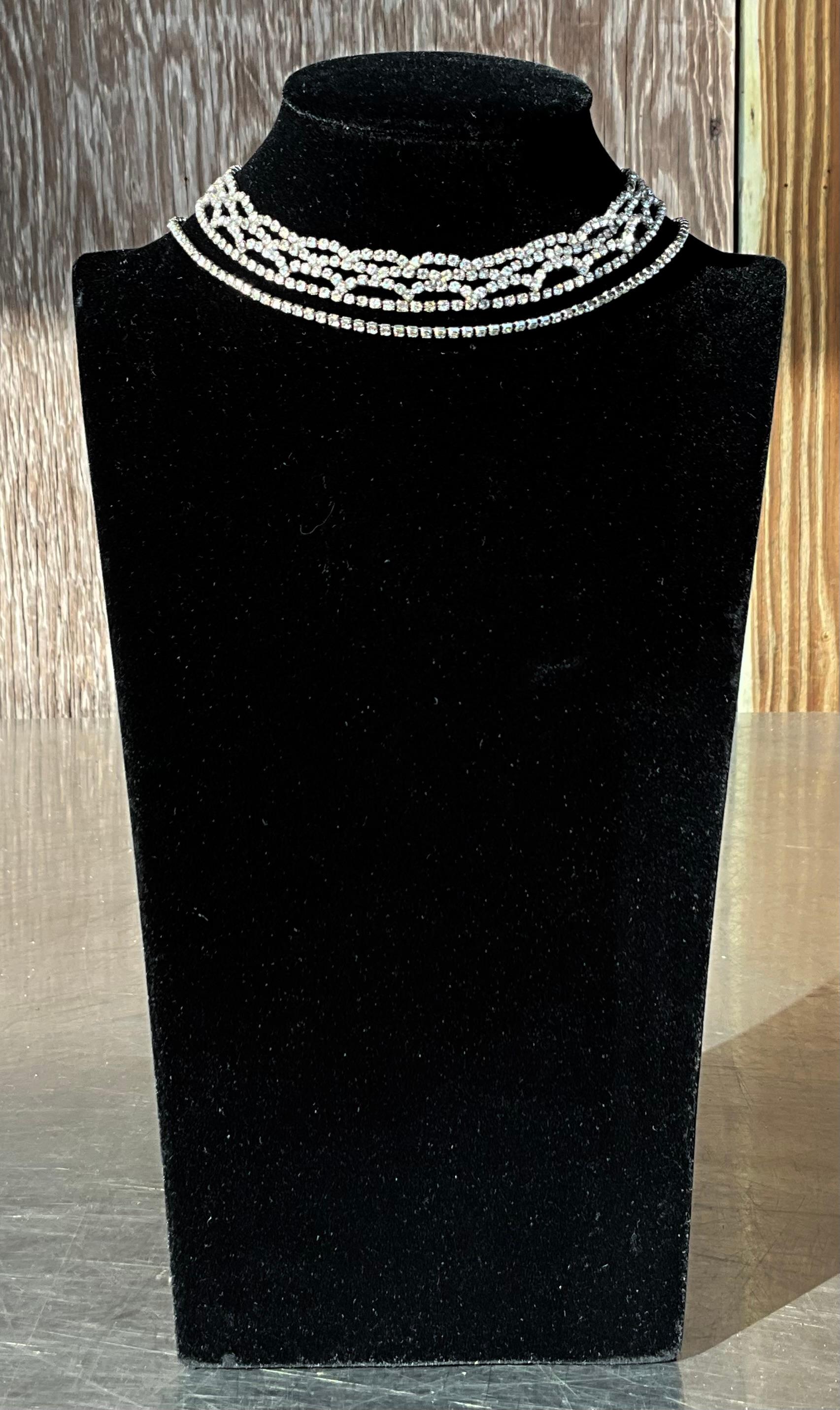 Questa collana vintage con strass è caratterizzata da un'abbagliante serie di strass, pietre chiare e sfaccettate che riflettono la luce in modo meraviglioso, imitando lo scintillio dei diamanti. Gli strass sono tipicamente incastonati in una