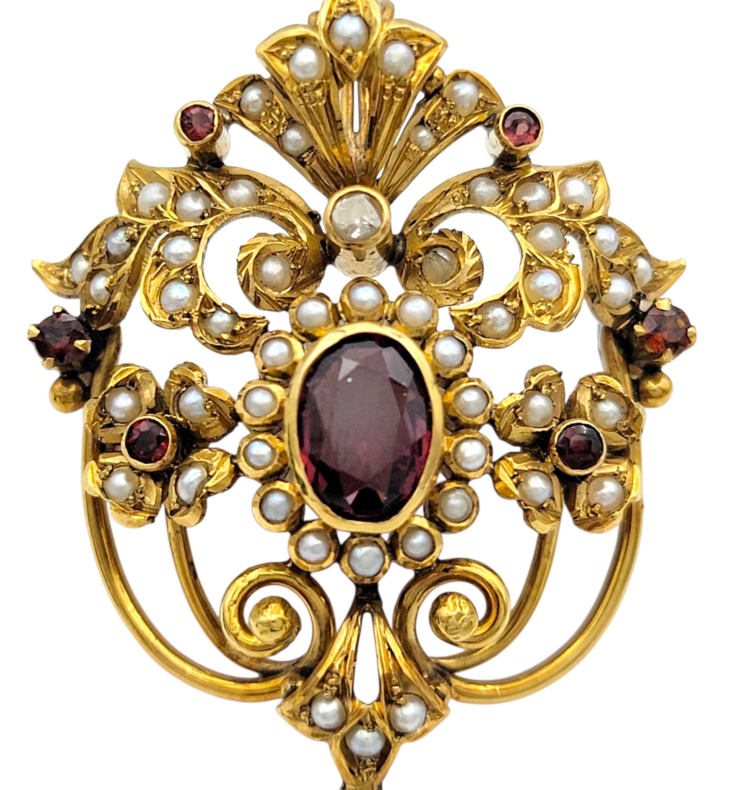 Diese kunstvoll verzierte Brosche ist ein detailreiches Stück aus 18 Karat Gelbgold. Sein Herzstück sind leuchtend purpurrote Rhodolith-Granate im ovalen und runden Schliff, die eine elegante und königliche Komposition bilden. Ein einzelner Diamant