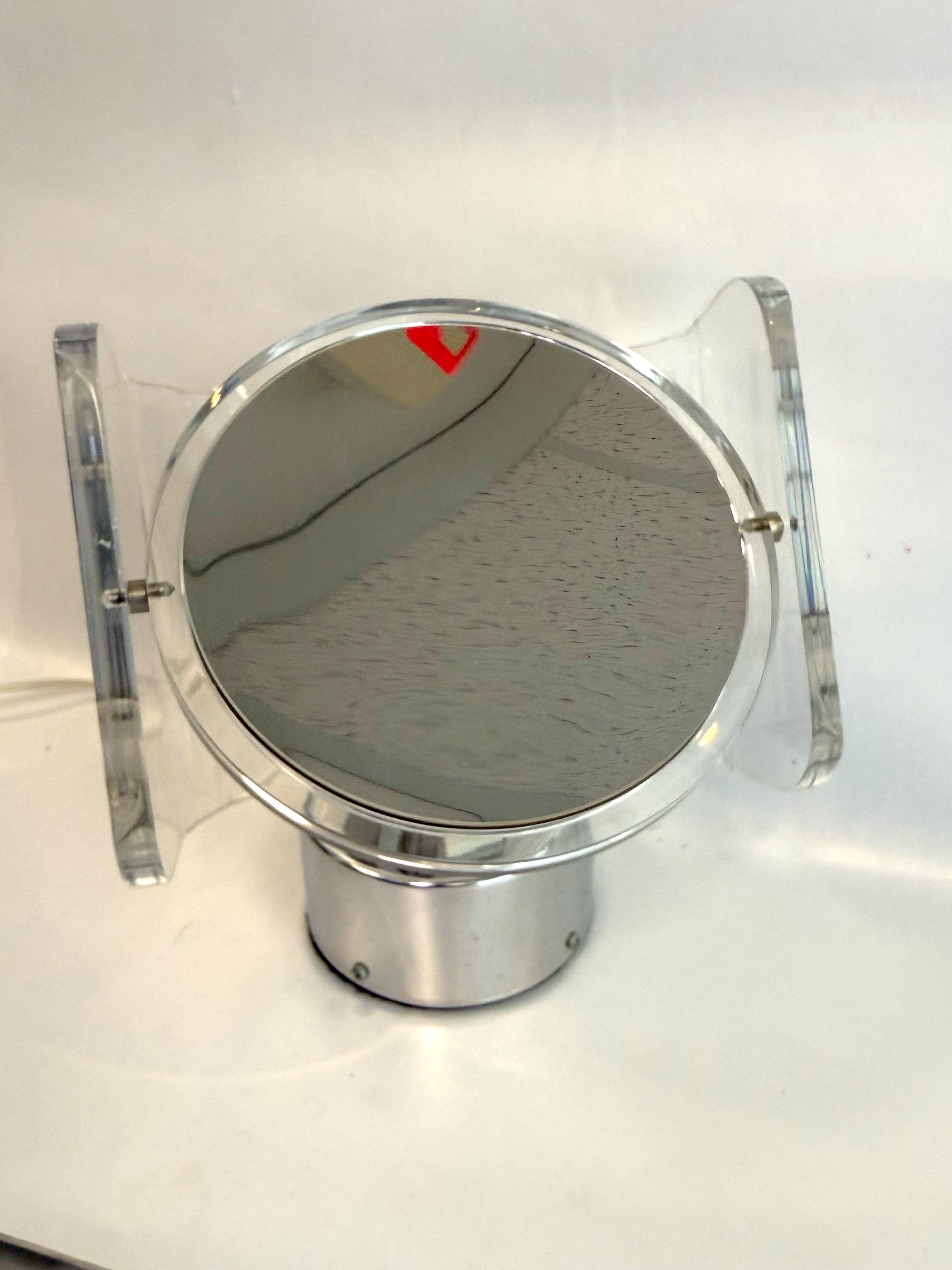 Double sided chrome and lucite lighted vanity mirror by Rialto. In excellent working condition. On side of mirror is 5x magnification the other is normal. Knob allows for adjusting brightness of light that illuminates through the lucite to the front