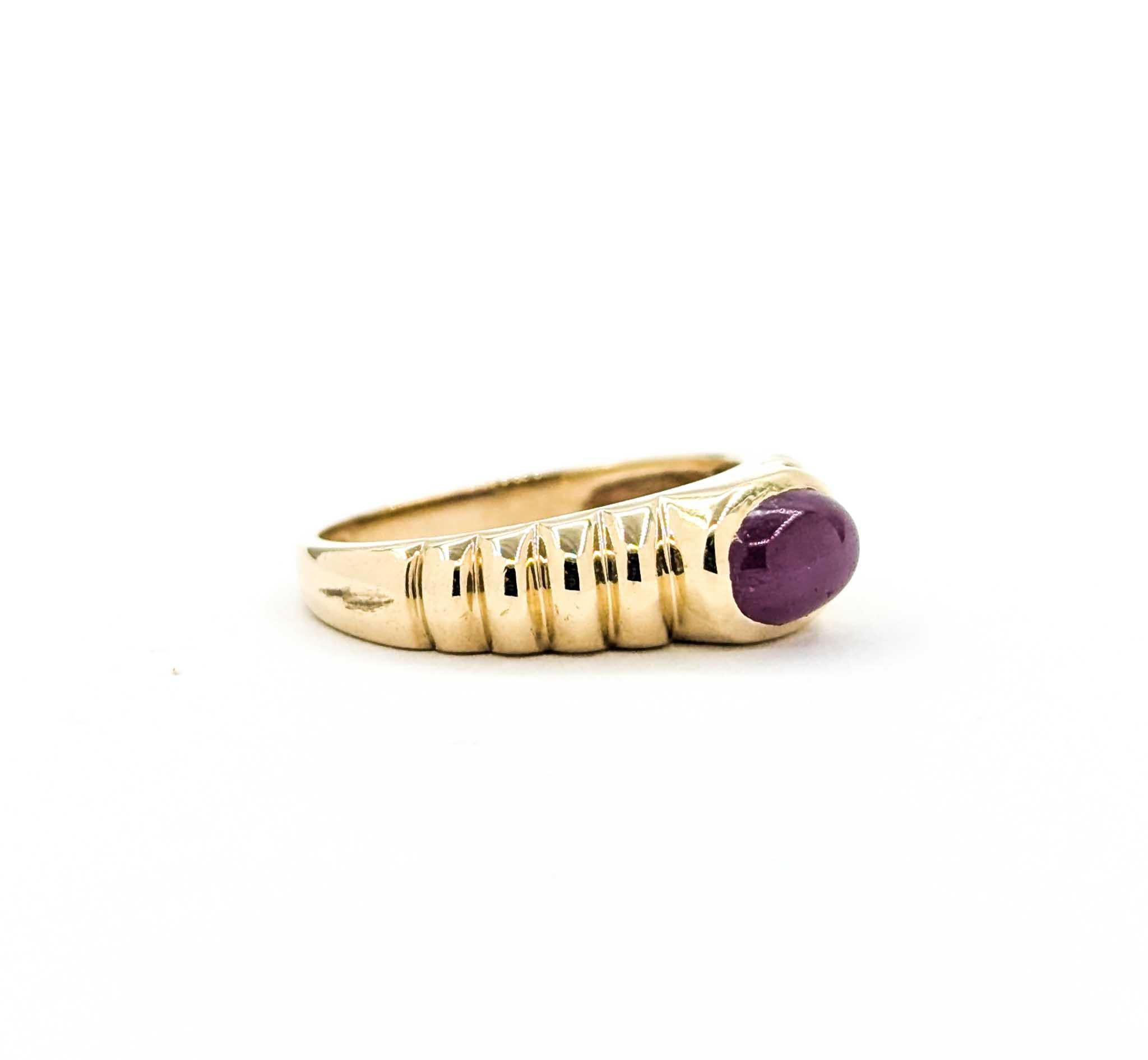 This vintage ring is crafted in 14k yellow gold and showcases a rich .80 carat cabochon-cut ruby at its center. The ruby’s deep red hue is beautifully highlighted by a ribbed gold band that adds dimension and texture to the design. Its sleek bezel