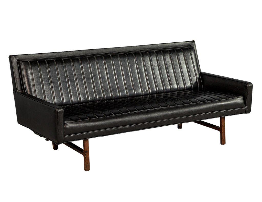 Classic designed Mid Century black vinyl sofa features a linear ribbed texture across the seat and back. This texture repeats across the vinyl at 4” intervals and perfectly aligns down the seam connecting the seat and sofa back. The small size and