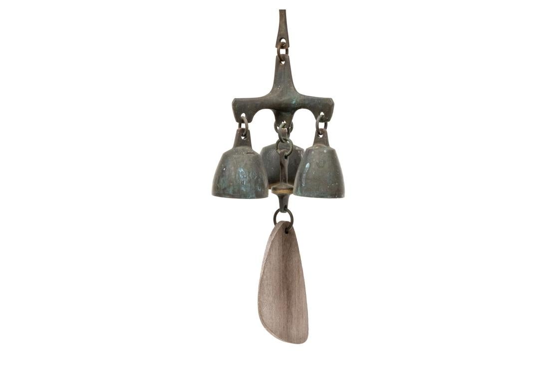 An Organic and solid feeling bell by Richard Fisher. Triple bell with fine high tinkling sound. A hanging section with intrinsic loop mounted to a tri-form section which the three bells. A central wooden abstract form hangs below. 

Dimensions: 2