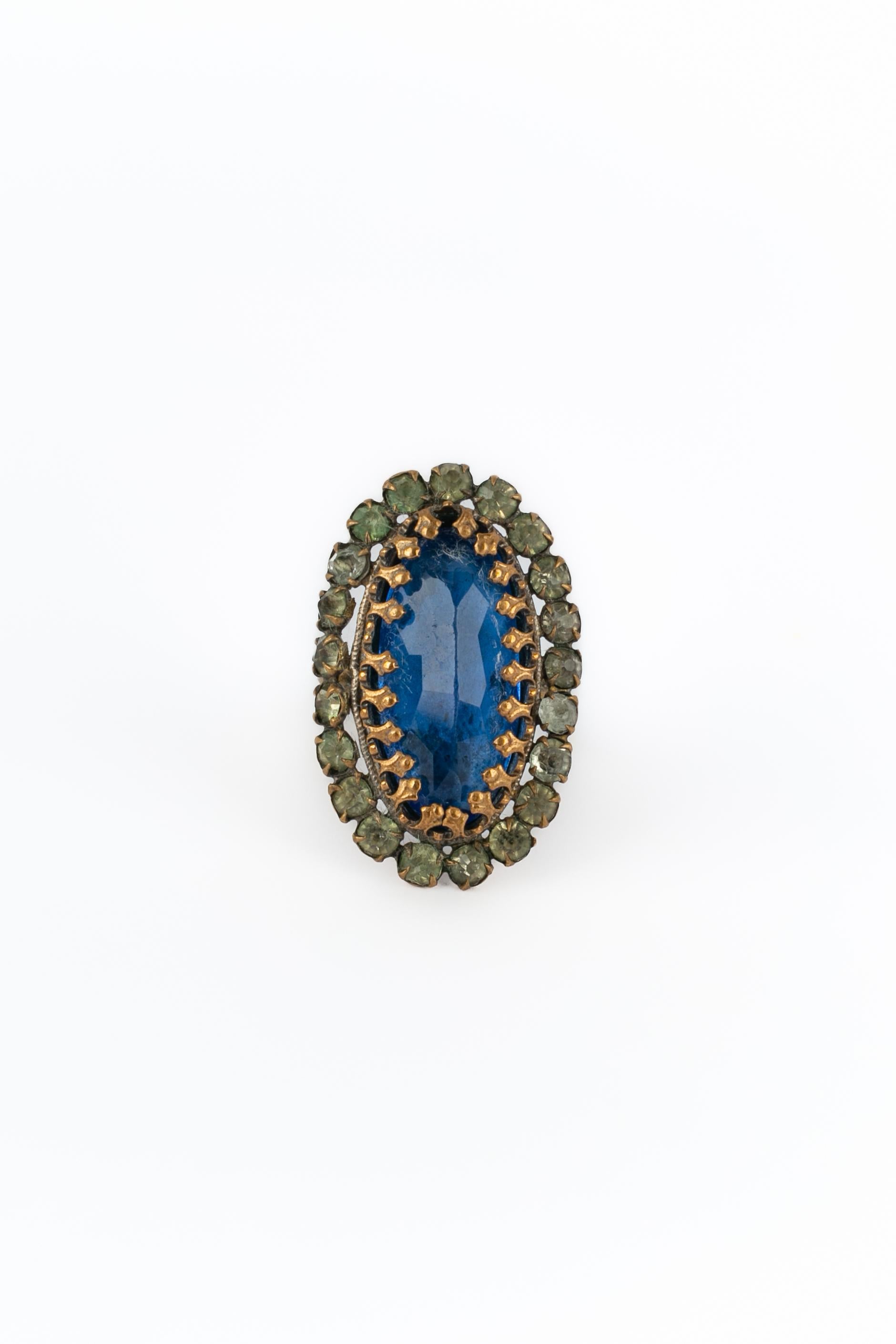 SCONOSCIUTO - Anello in metallo dorato scuro con uno strass blu bordato da altri strass.

Condizioni:
Buono stato

Dimensioni:
Taglia 55/56

SKU:BG24