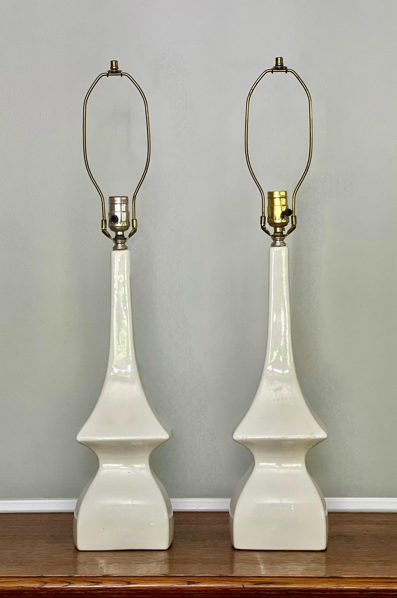 Striking pair of white modern sculptural glazed ceramic lamps by Robert Abbey, New York, mid 20th century. An elegant, curvilinear form and a vibrant shade of creamy white together create a crisp, clean and modern silhouette. They are in good