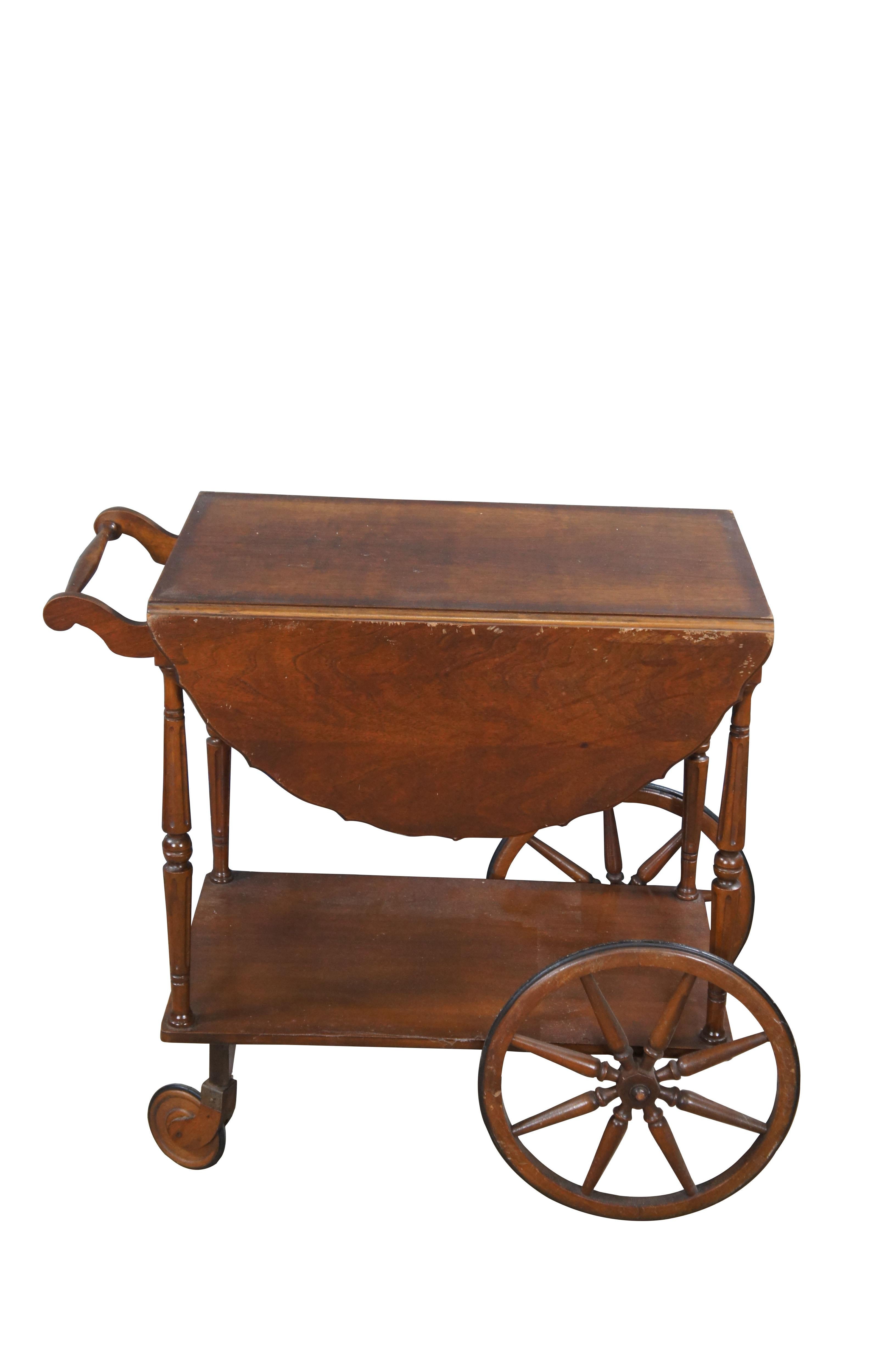 Antique Robert Mitchell tea / bar / serving cart.  Made of walnut featuring a two tier design with scalloped drop leaves and removable glass tray table with handles.  Includes one drawer, large wagon style wheels and rolling castors.

Robert
