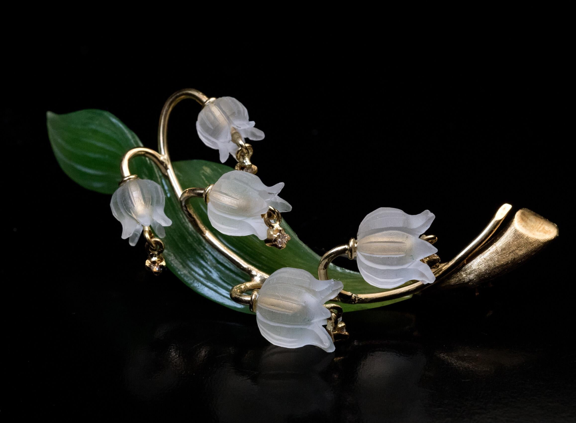 Austria, circa 1960s  The brooch is finely modeled as a lily of the valley. The flower heads are superbly carved from frosted rock crystal and embellished with small diamonds. The green leaf is naturalistically carved from a single piece of nephrite