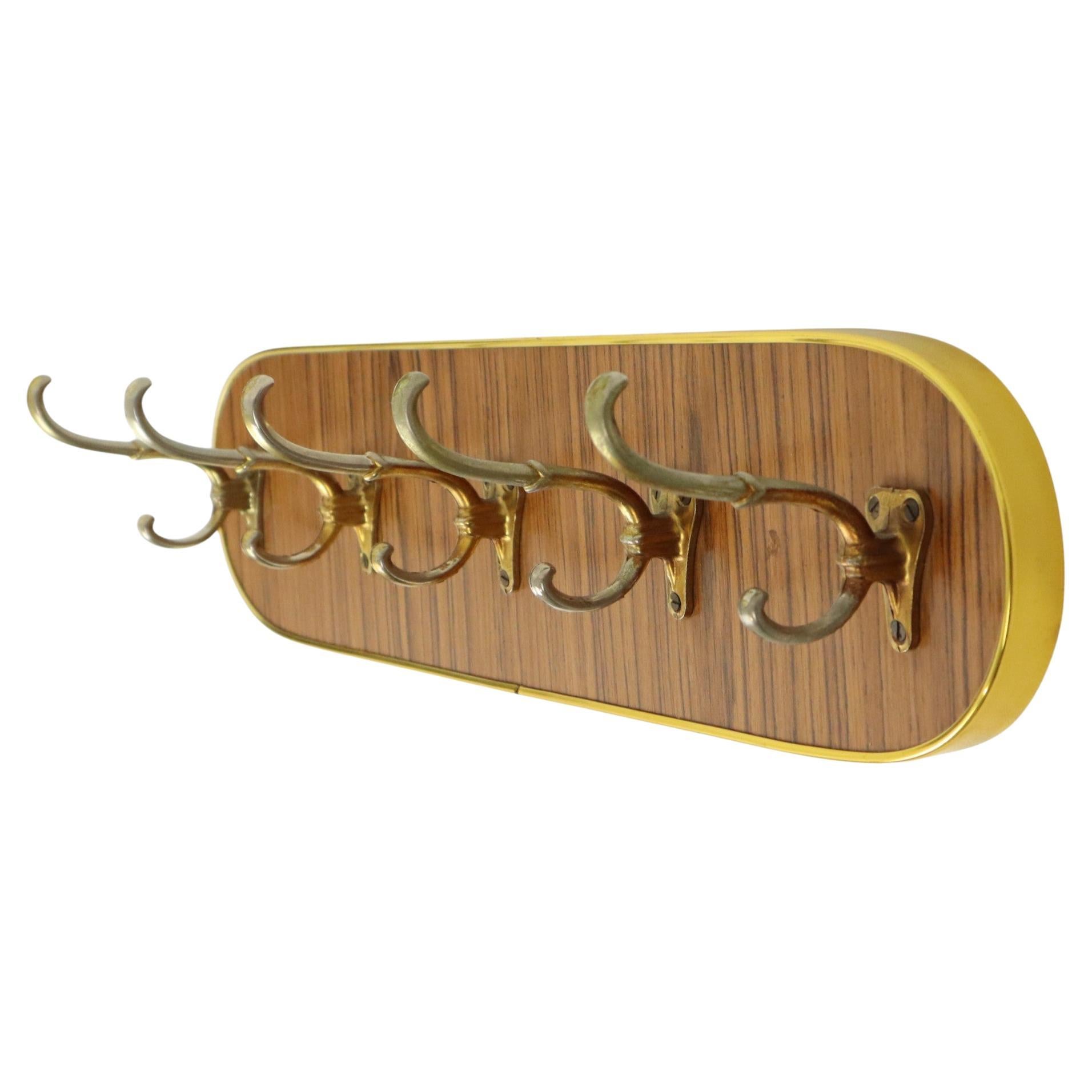 Cool vintage wall coat rack, coat rack with 5 hooks, completely in the typical 50s rockabilly style, a rounded wooden surface finished with wood veneer and a gold plastic band all around, 5 large metal hooks that are copper-plated, Belgium 1950s