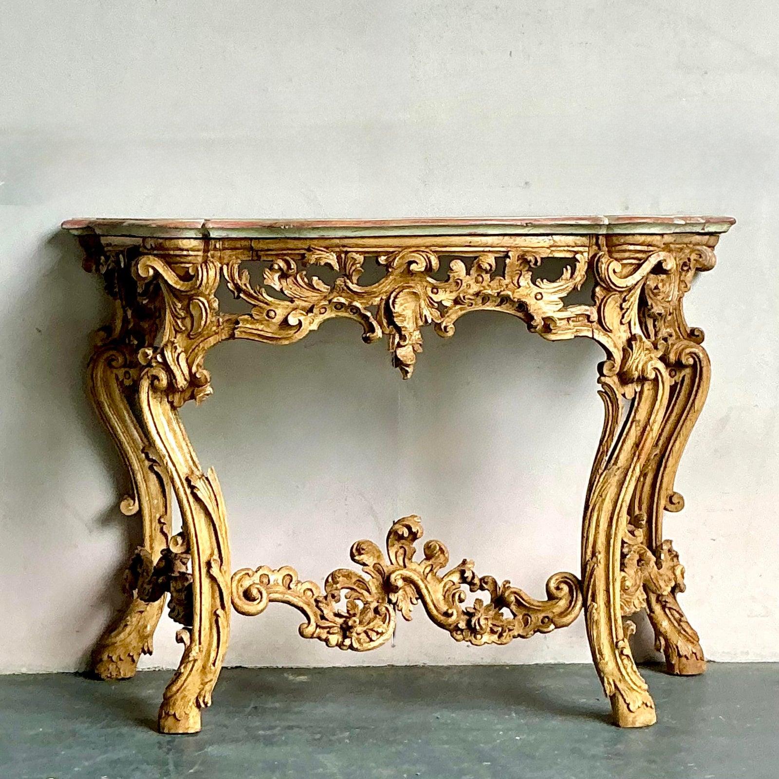 Entra in un mondo di opulenta eleganza con questa squisita consolle rococò vintage, una vera e propria testimonianza della grandezza del design europeo del XVIII secolo. Questo splendido pezzo presenta un'abbondanza di dettagli magistralmente