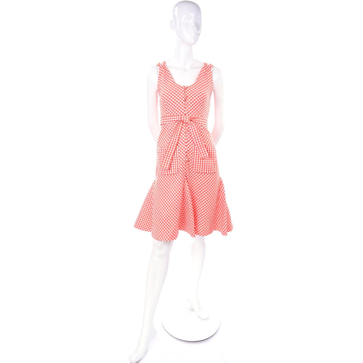 This is such a fun dress designed by Albino Rodrigues. This orange and white gingham  dress has a cross back with double straps and a matching fabric sash or tie that can be worn as a belt or a neck/hair tie. There are two patch pockets at the hips