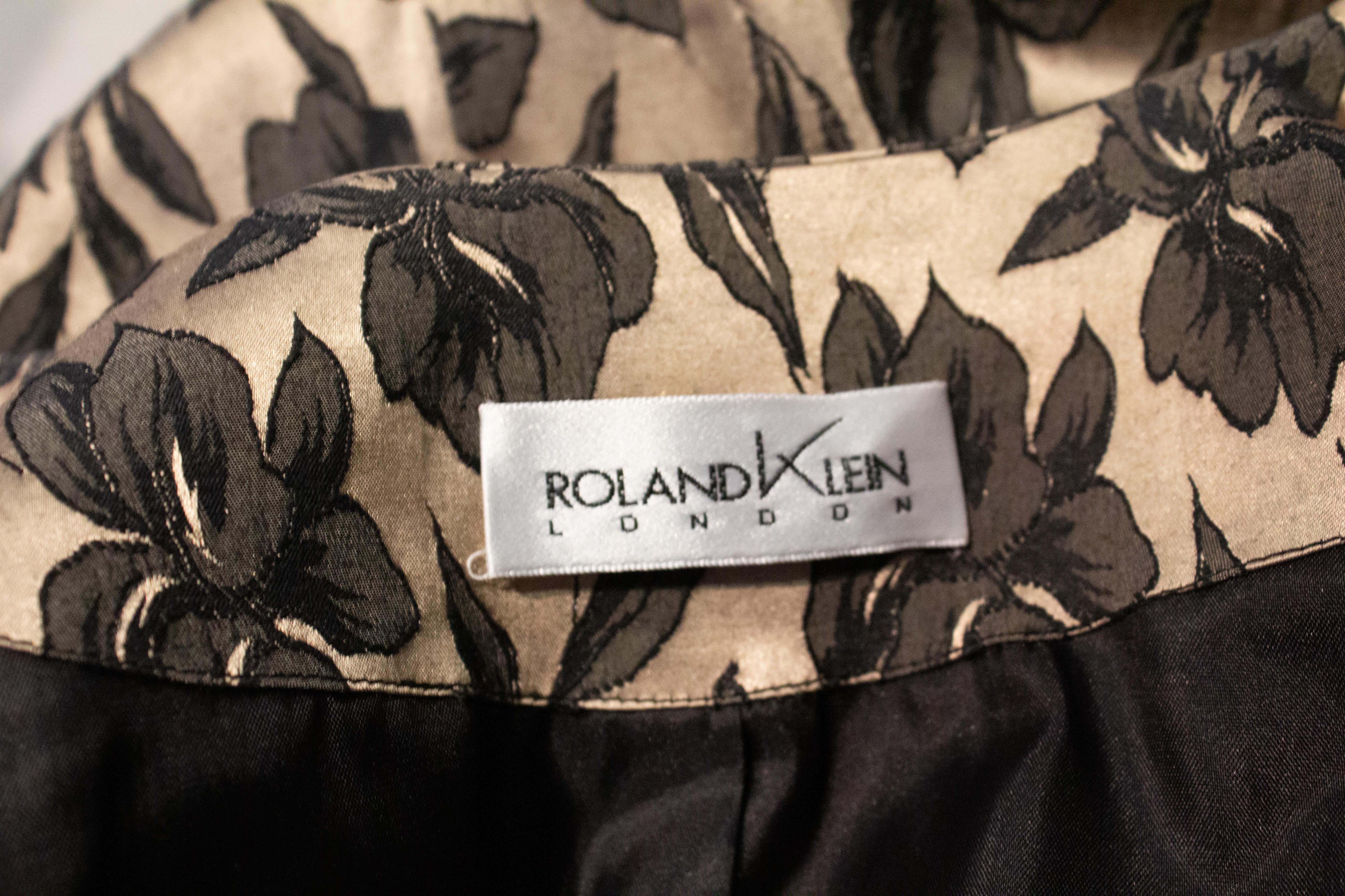 A chic vintage evening coat by Roland Klein. The coat is in a soft gold colour with a black leaf pattern. It has a round neckline, elbow length sleaves and a pocket on either side.
Marked a size 10 , bust up to 38'', length 36''