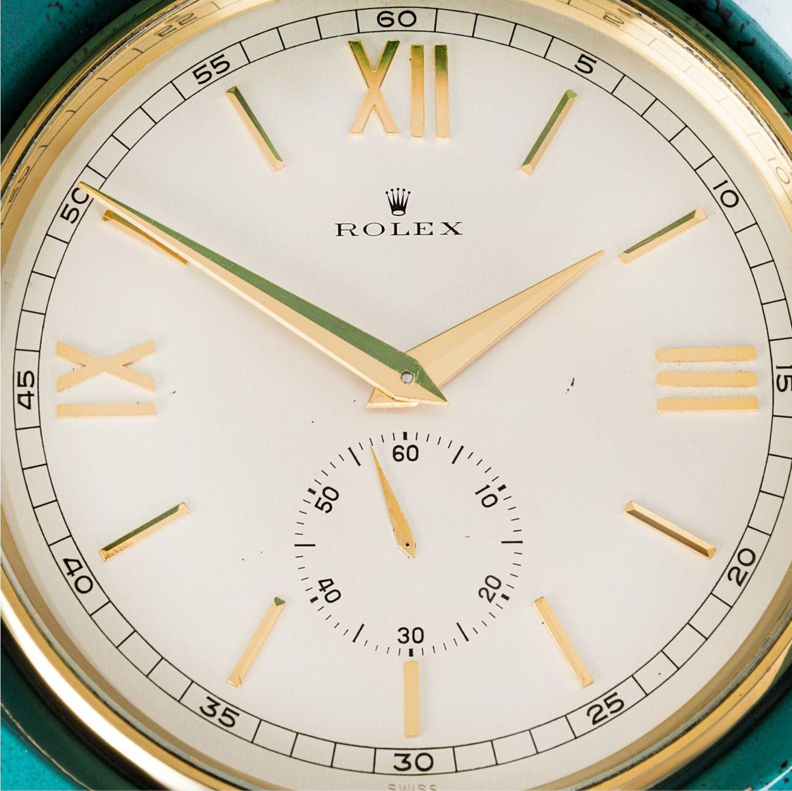 Rolex. A Gilt Brass Painted Horseshoe-shaped Desk Clock, La Hora Al Secundo with Original Wooden Presentation Box C1960.

Dial: A Matt Silvered Dial, Signed Rolex, with applied Roman numerals, outer minute track subsidiary seconds dial at six with