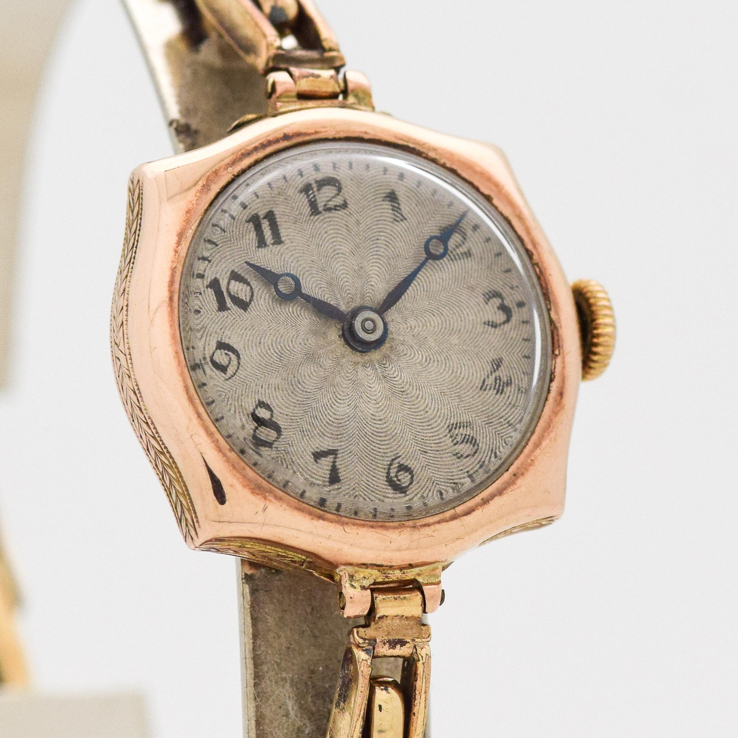 Montre Art Déco vintage Rolex pour femme en or rose clair 9k des années 1910, avec cadran argenté d'origine, chiffres arabes Breguet noirs et bracelet stretch à ressort d'origine.  23 mm x 27 mm d'une patte à l'autre (0,91 in. x 1,06 in.) -