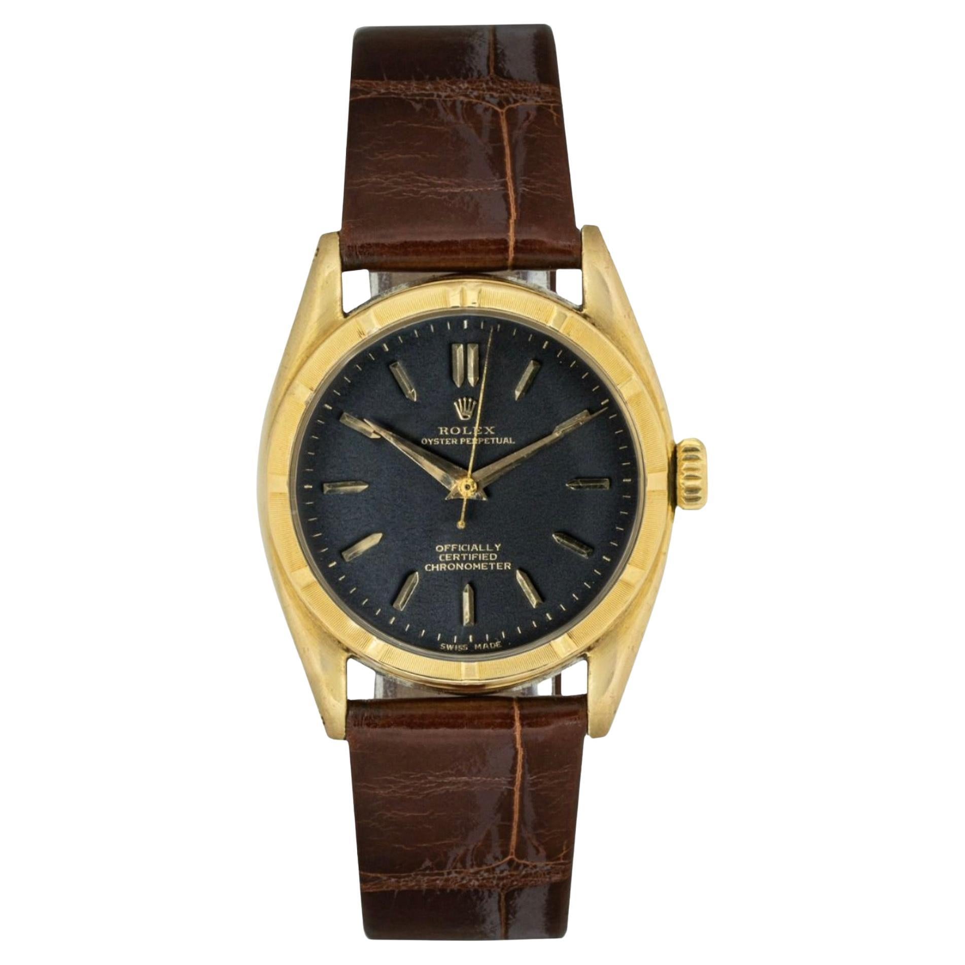 Eine Oyster Perpetual Armbanduhr aus Gelbgold. Sie verfügt über ein unverwechselbares mattschwarzes Zifferblatt mit applizierten Indexen und eine Lünette aus Gelbgold mit gedrehtem Motor. Ausgestattet mit einem generischen braunen Lederband und