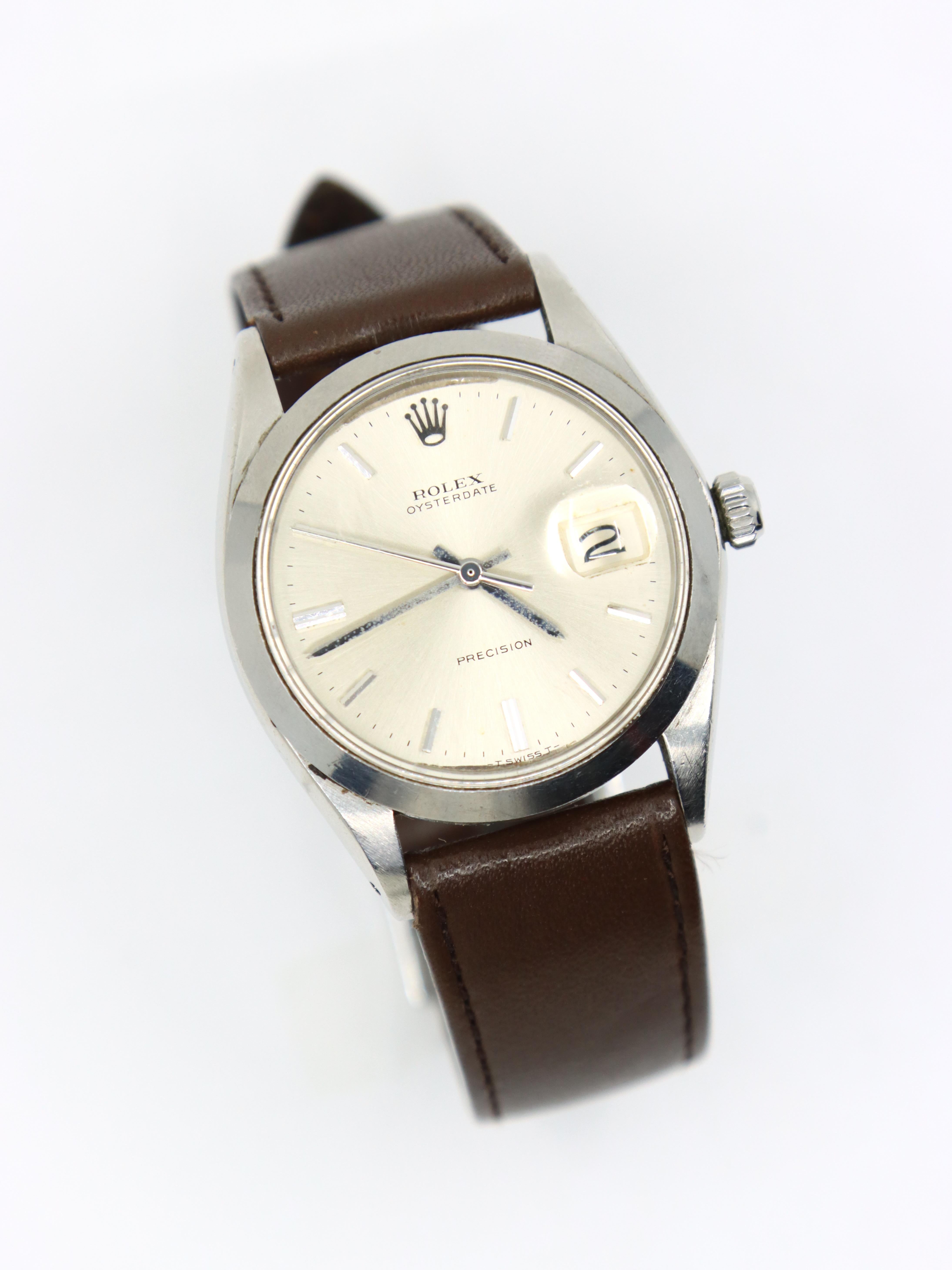 Vintage ROLEX Oysterdate Precision Date Uhr mit braunem Lederarmband

Markiert:
ROLEX
ACIERINOX
SWISS MADE

Ungefähre Abmessungen:
25 cm (Länge)
34 mm (Gehäusedurchmesser)
1,9 cm (Riemenbreite) 
46,5 Gramm Gewicht.
