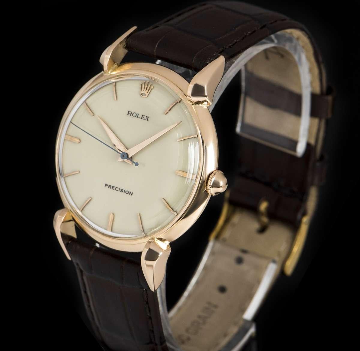 An 18k Rose Gold Precision Vintage Gents Wristwatch, cream enamel dial with applied hour markers, a fixed 18k rose gold smooth bezel, 18k rose gold tear drop lugs, a brown leather strap (not by Rolex) with an original gold plated pin buckle, plastic