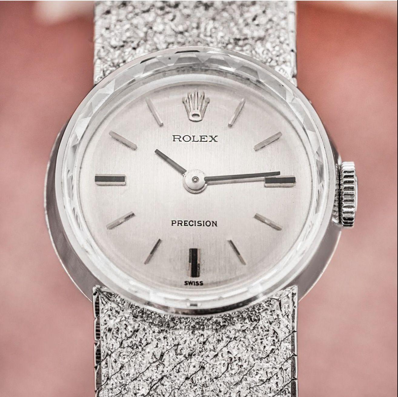 A ladies Rolex Precision white gold wristwatch. Featuring a silver dial with applied hour markers.

The watch is equipped with an integral white gold bark effect bracelet and a white gold jewellery style clasp. Fitted with a plastic glass and a
