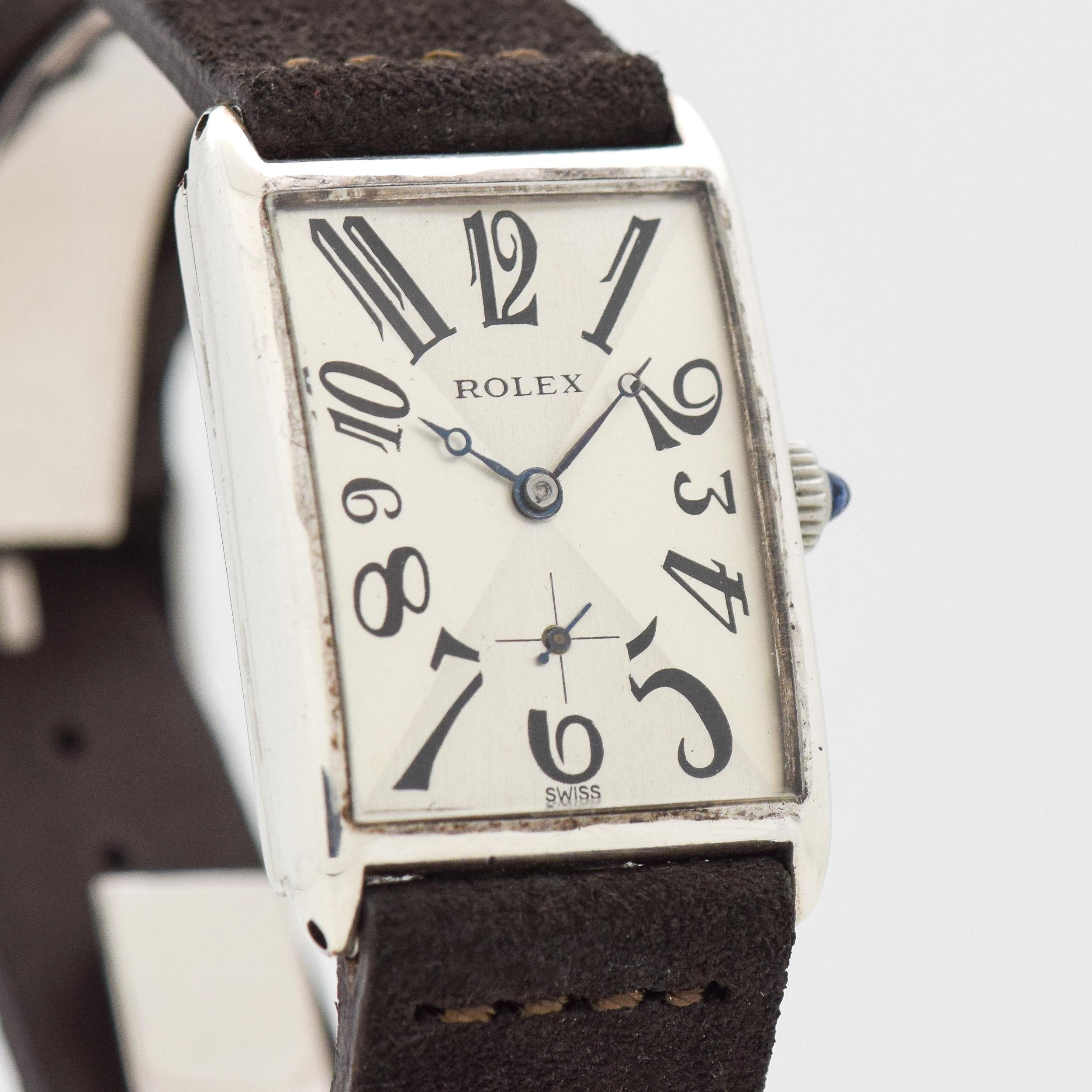 1930's Vintage Rolex Rectangle Sterling Silver Case watch with Two Tone Silver and Gray Dial with Black Exploded Breguet Arabic Numbers. 25mm x 38mm lug to lug (0.98 in. x 1.5 in.) - 6 jewel, manual caliber movement. Featured on a Sueded Genuine