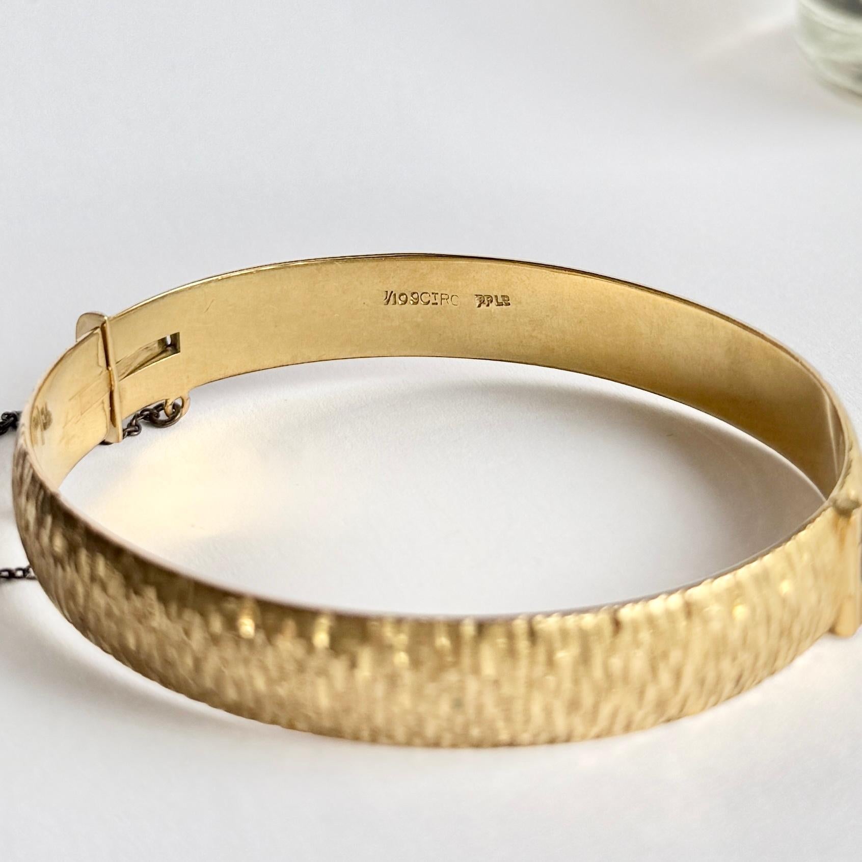 Este precioso brazalete de oro laminado de 1/10 de 9 quilates tiene un grabado maravilloso. Oro laminado significa que el núcleo es de metal y tiene una fina capa de oro en la parte superior. 

Circunferencia interior:  17cm
Ancho del brazalete: 10