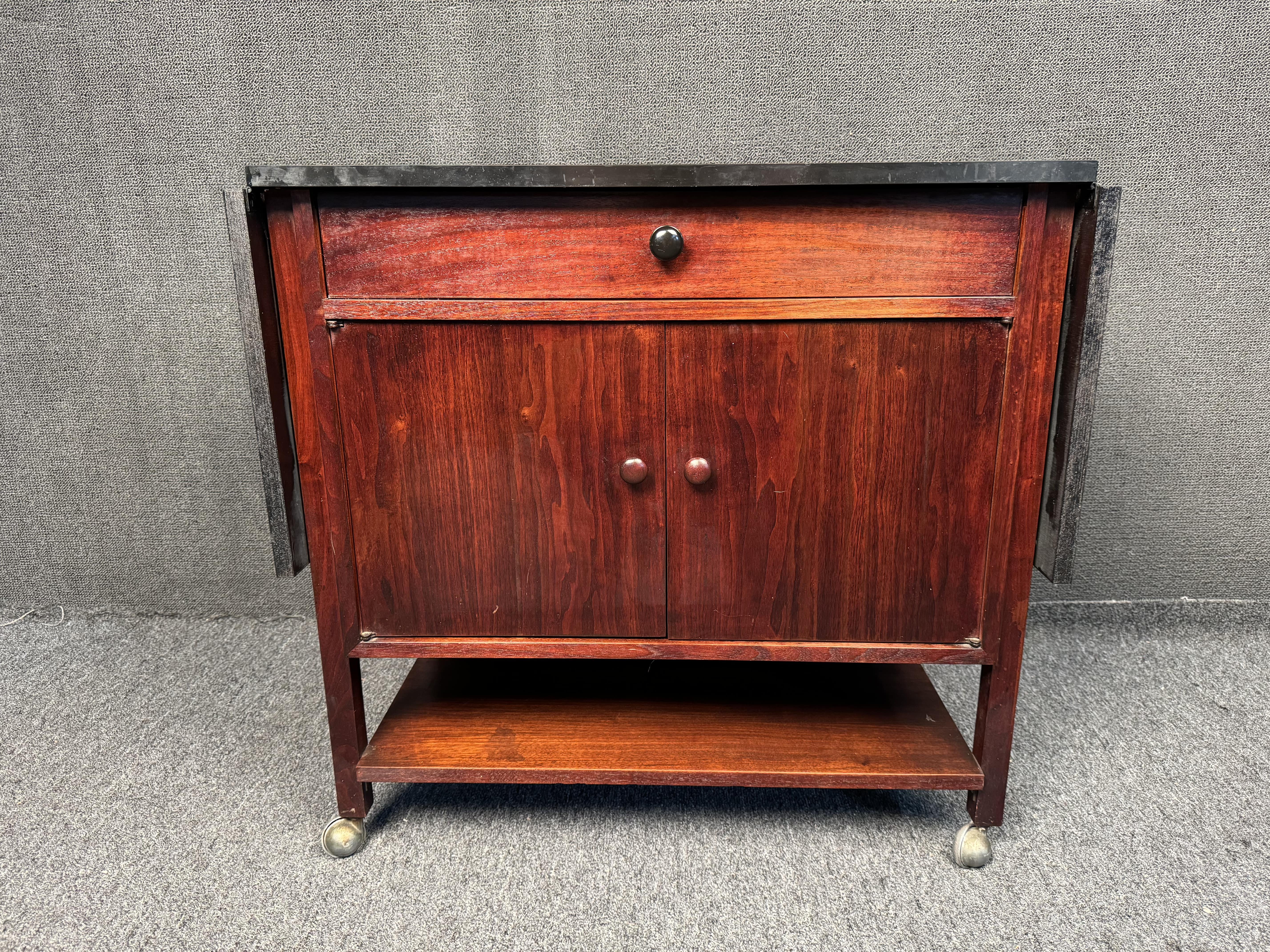 For your consideration, a quaint drop leaf bar/kitchen cart. Featuring an expanding leaf top, rolling casters, top drawer for cutlery, and bottom cabinet section to store your alcohol. Please confirm location with seller, (NY or NJ)
