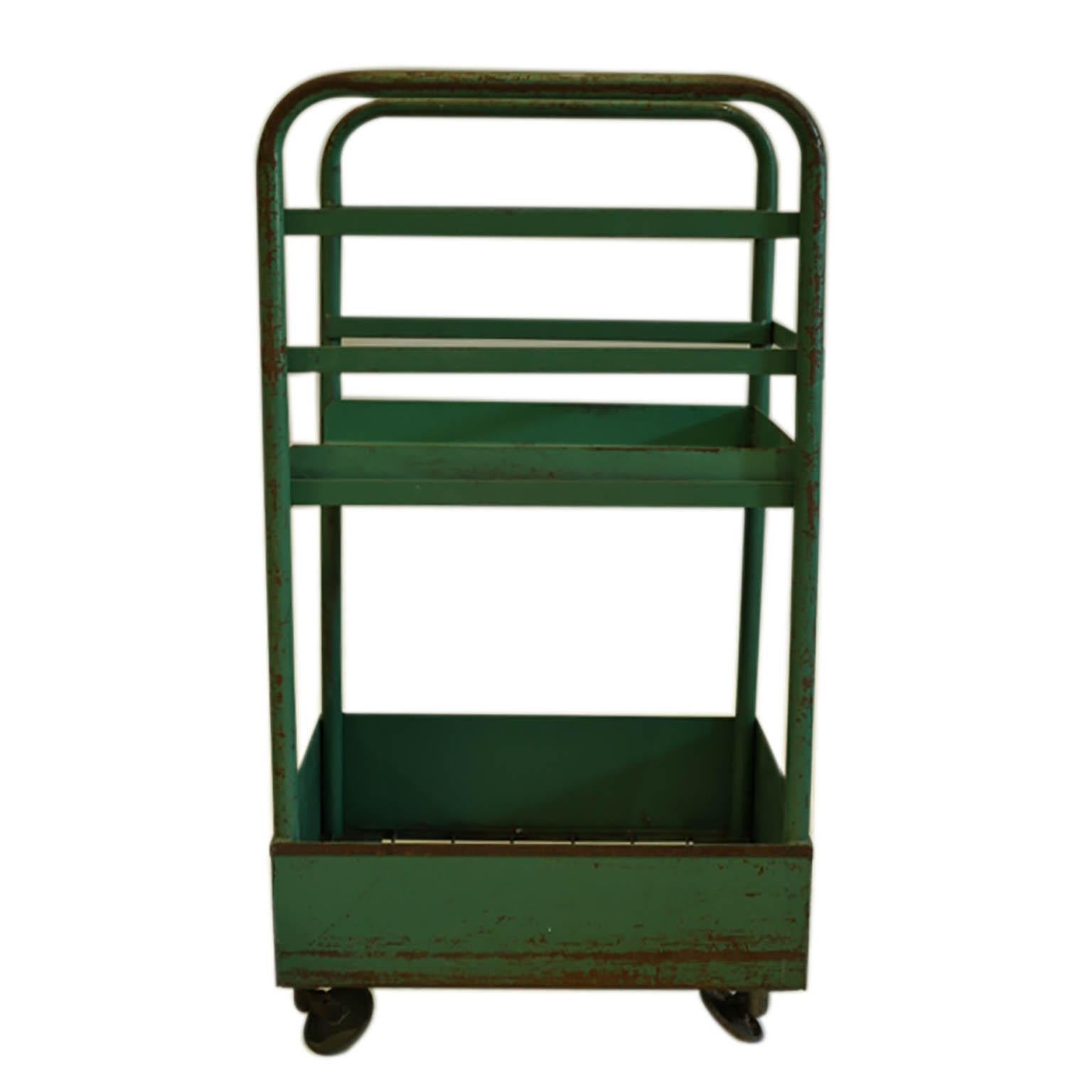 Industrial steel factory cart with original green paint. The top tray is removable and is open on one side. All four wheels are at a 45 degree angle, presumably to spin around easily on the factory floor. Original purpose unknown.