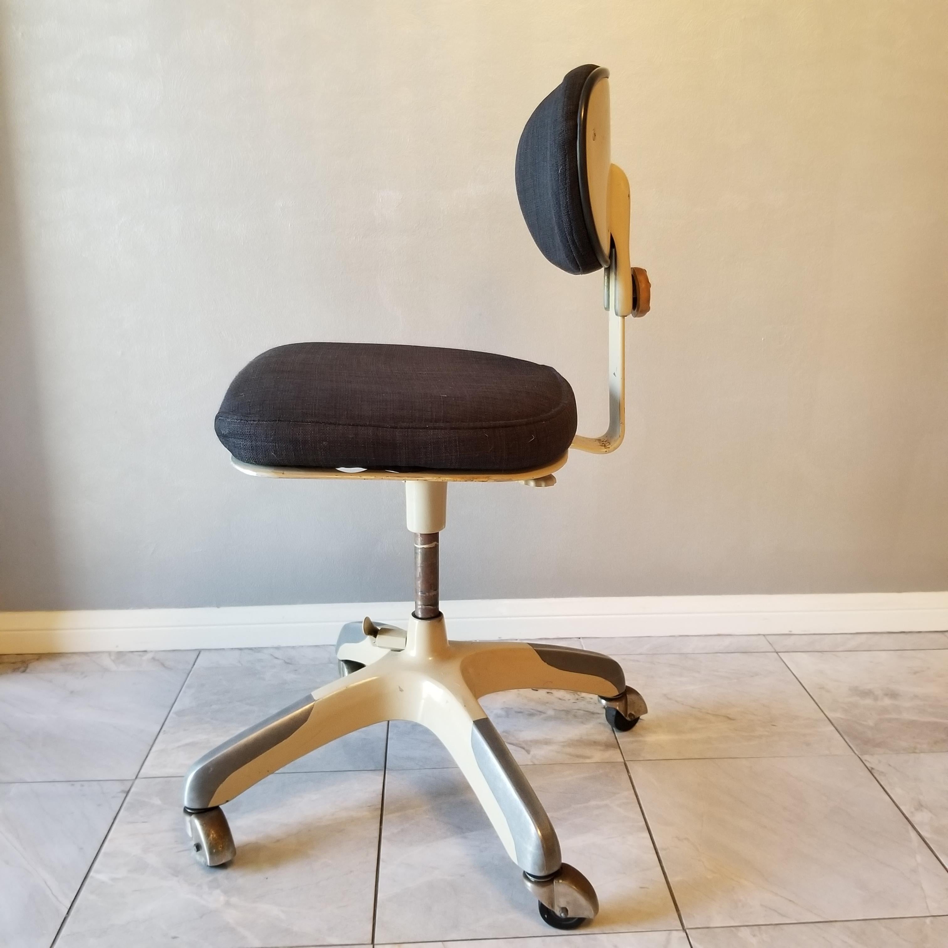 A midcentury Classic: 1950s vintage office desk chair by Cramer Company of Kansas City, a rolling tanker business chair.
This is their air flow posture chair model.
Colors are black fabric on a cream and silver metal base. Chair screams 1950s