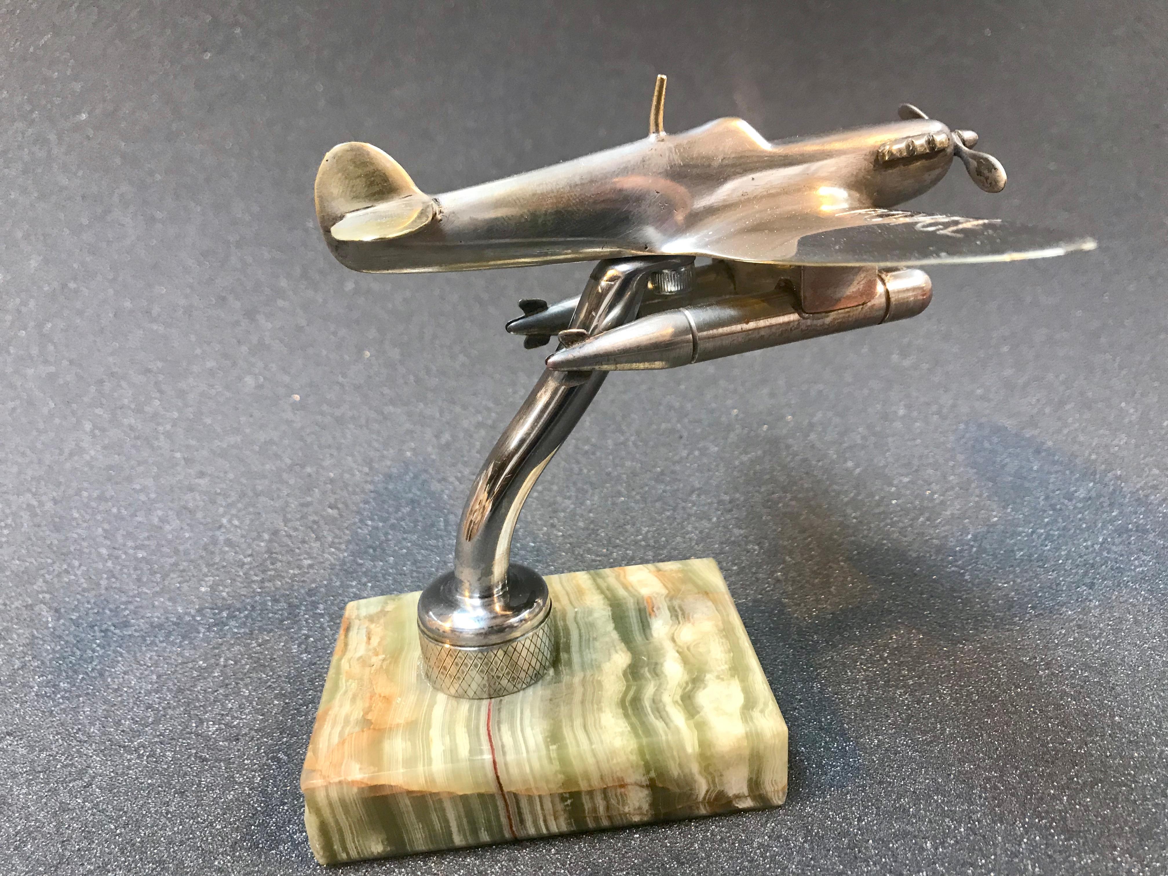 Chromium-plated on brass, the inscription Rolls Royce embossed on the wings. 

In the style of a single engine “Spitfire-type” fighter plane with two torpedo style tanks slung below. Attached to an onyx base
14 cms across ( Wing tip to wing