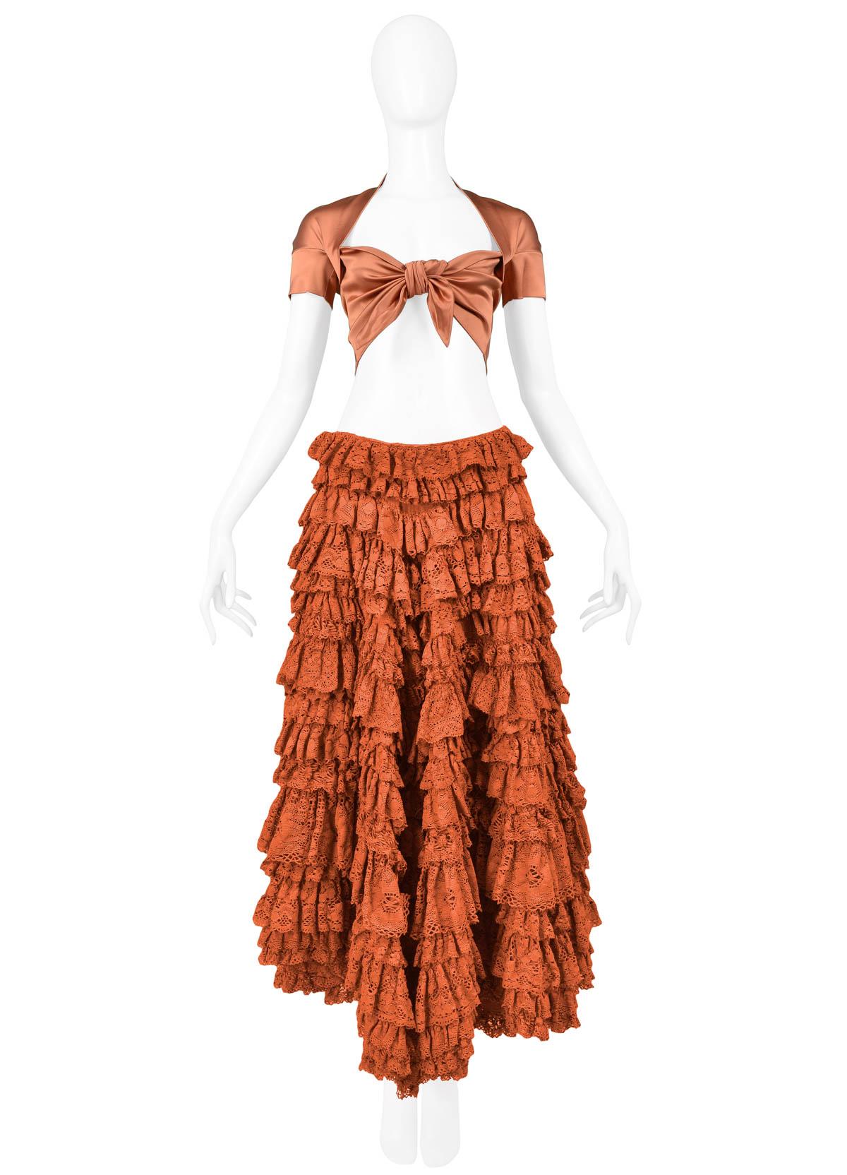 Vintage Romeo Gigli rust satin lycra top with cotton lace skirt ensemble. Top features crop fit, knot tie front closure, and short sleeves. Patio skirt features heavily ruffled cotton lace multi-tiers, high-low hem, and a side zipper closure. From