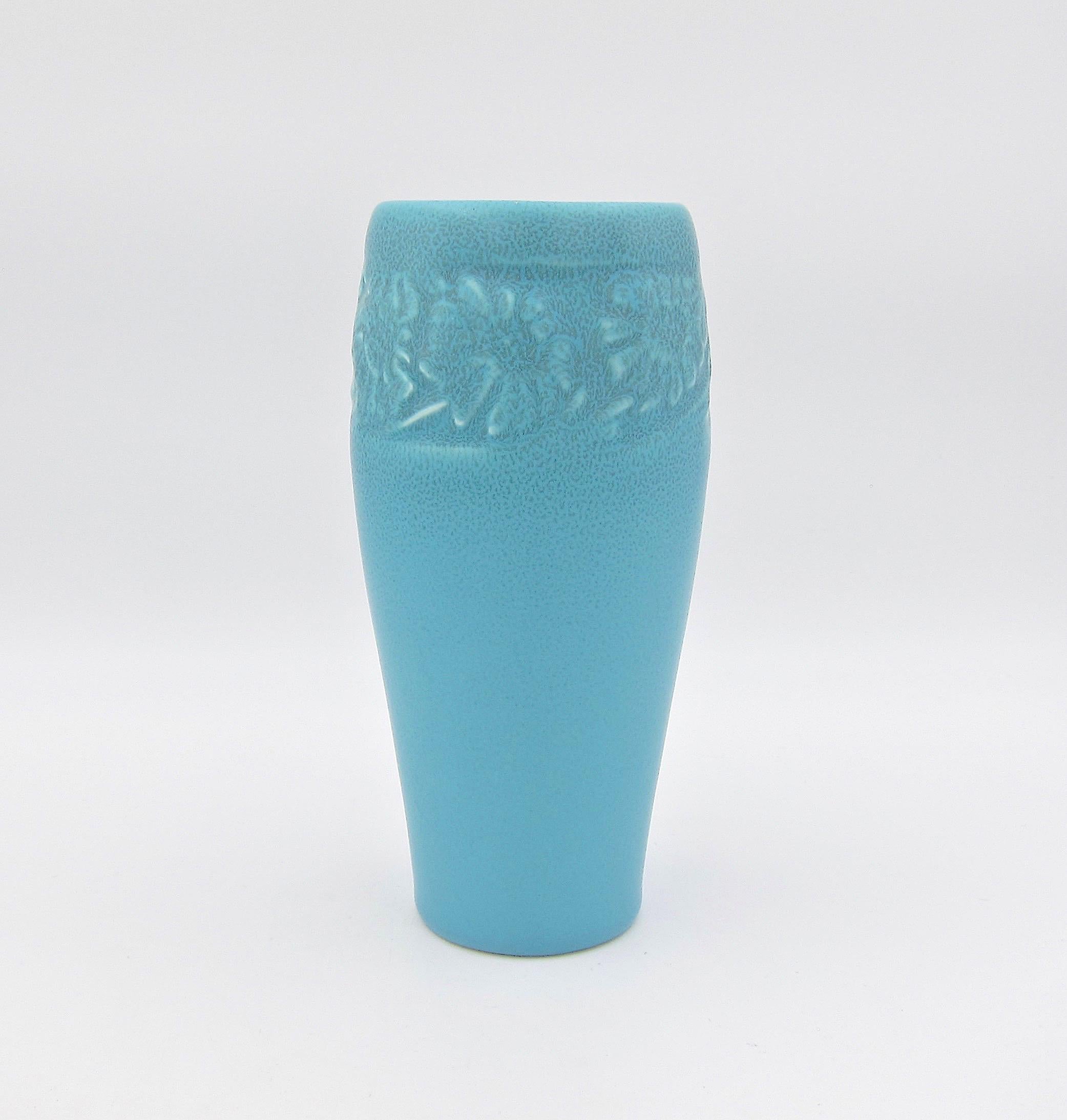 A vintage Rookwood Pottery Arts & Crafts production vase with a blue matte glaze made in 1930. This elegant American vessel is decorated with a molded band of sunflowers just below the rim.

Good condition with a small glaze loss/nick at the rim