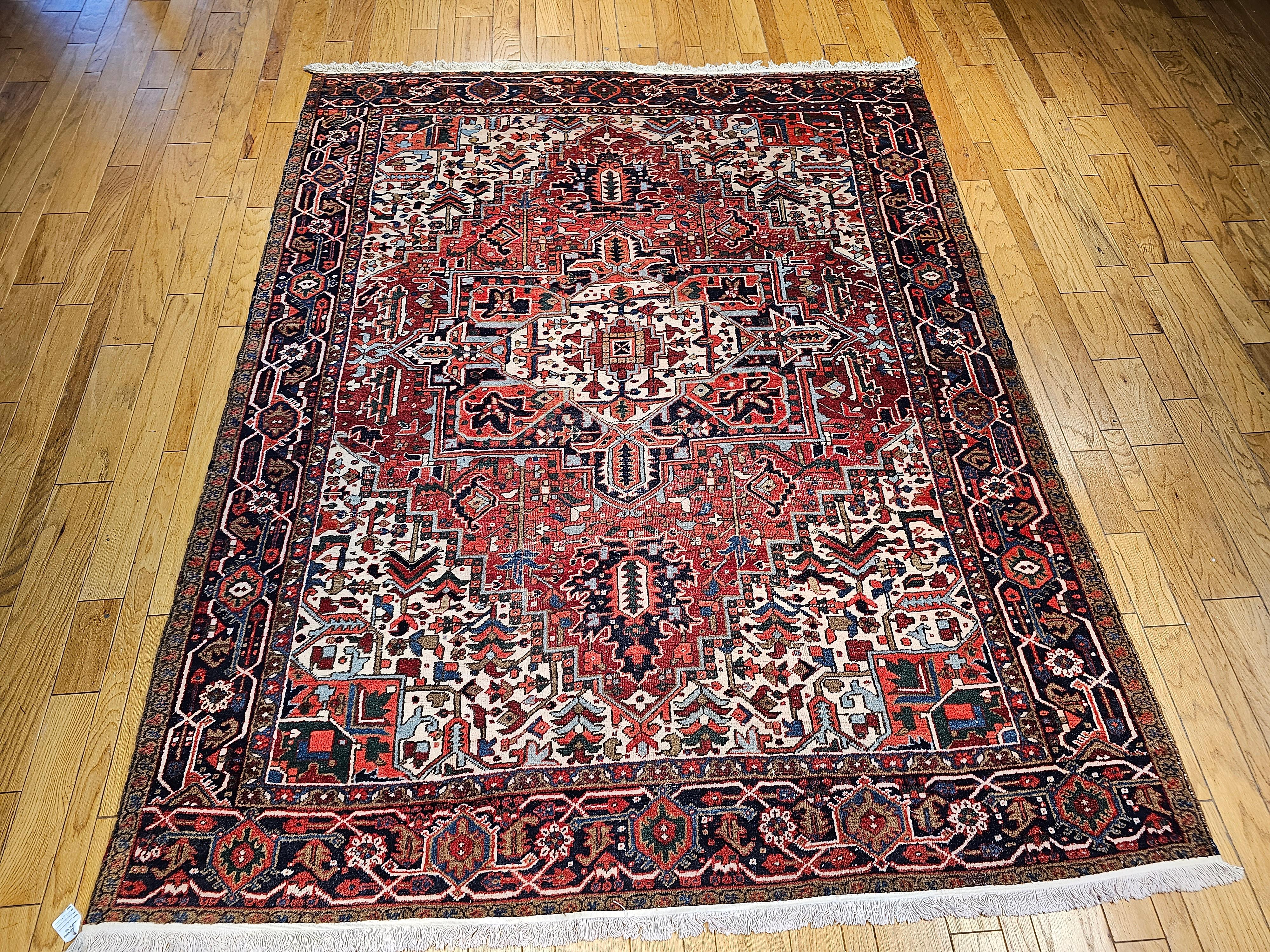 Beautiful and very colorful vintage Persian Heriz room size rug from the first quarter of the 20th century.  The field is a dark red or a brick red color with the central medallion in white with the medallion corners in blue and red with accent