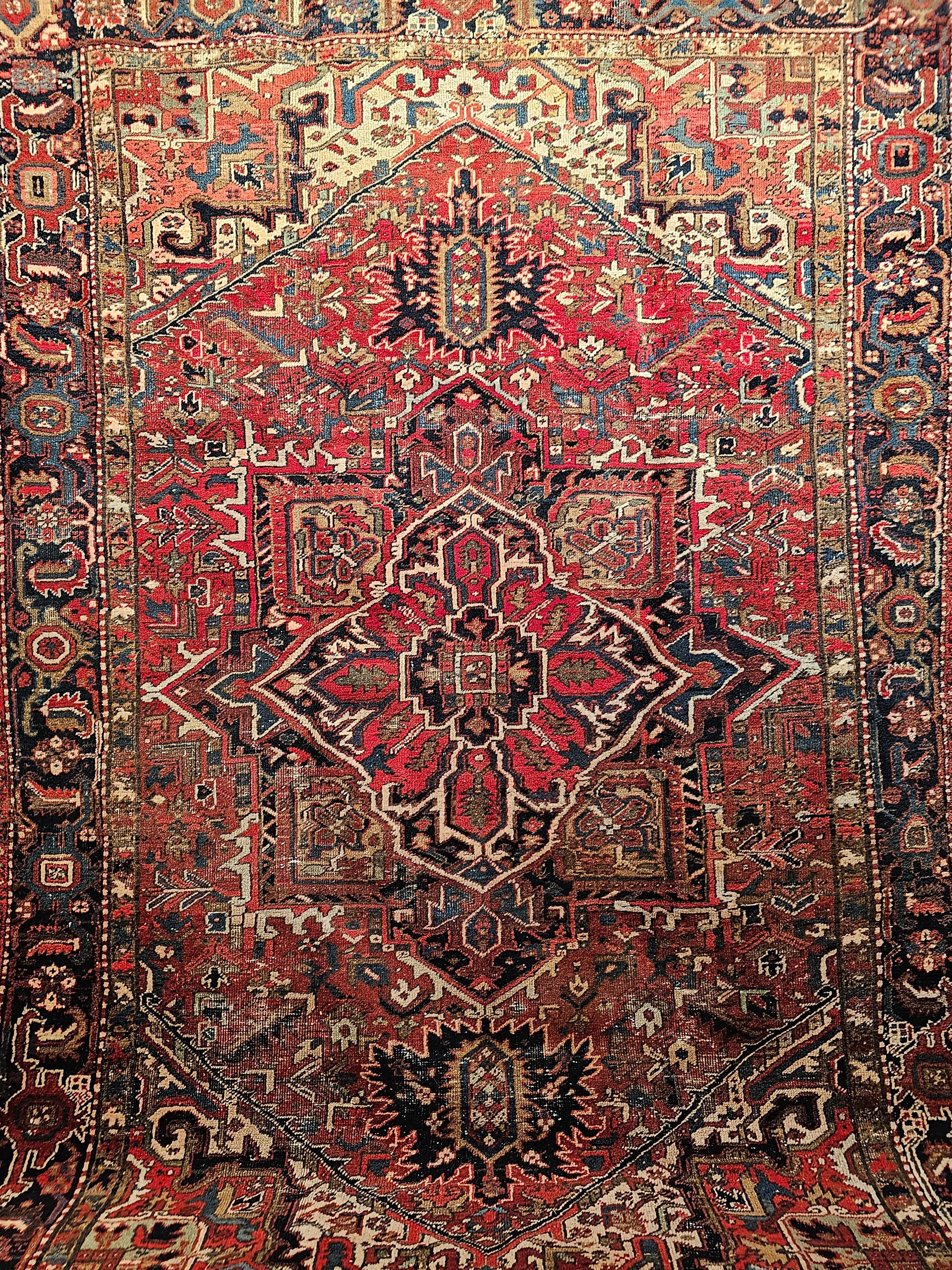 Beautiful and very colorful vintage Persian Heriz room size rug from the 1st quarter of the 20th century.  The primary color in the field is red with a central medallion center in red and the medallion corners in mustard yellow with accent colors in