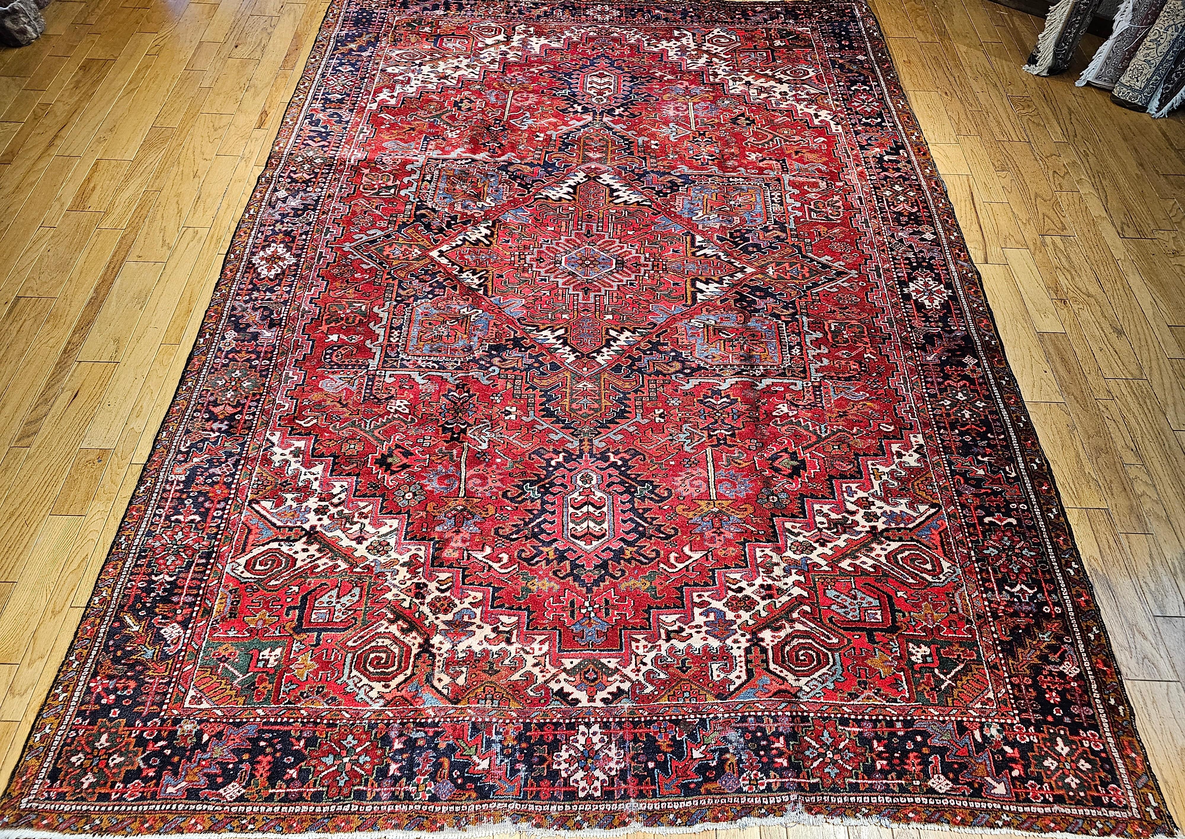 The vintage Persian  Heriz rug from the early 1900s has a great room size dimensions unlike most larger Heriz rugs that are narrow and long.  The rug comes in a geometric pattern with a central medallion in a beautiful red background.  The corner