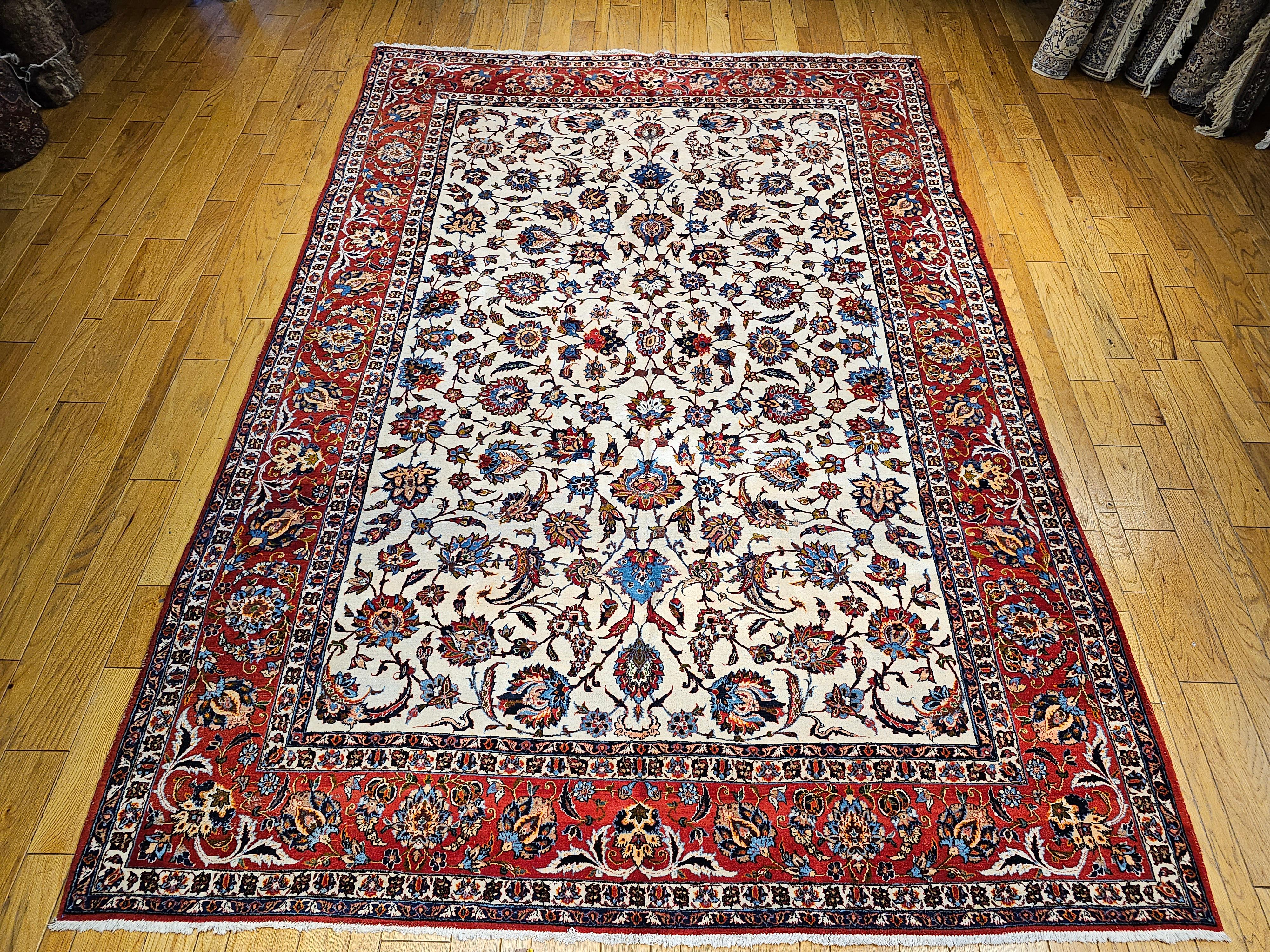  A room size Persian Isfahan in an allover floral pattern set in an ivory color field and a red border from the 2nd quarter of the 1900s.  The rug has a Shah Abbas large format “Leaf and Sickle” design with scrolling vines and leaves.  The design