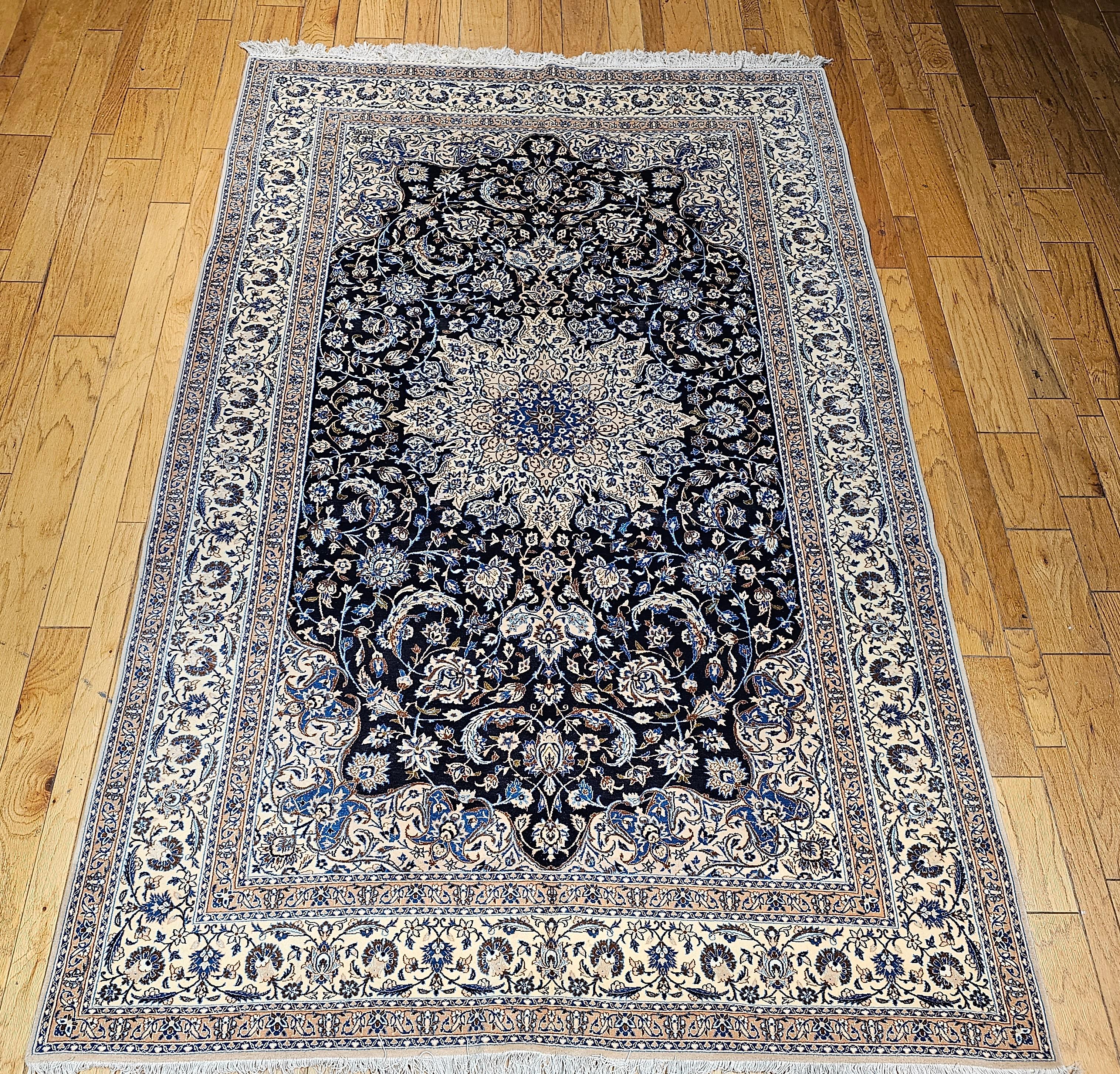 This finely hand knotted Persian Nain rug, crafted in the 3rd quarter of the 1900s, is a true masterpiece of traditional Persian artistry. Featuring an intricate floral design on a rich navy blue field, framed by an elegant ivory border, this