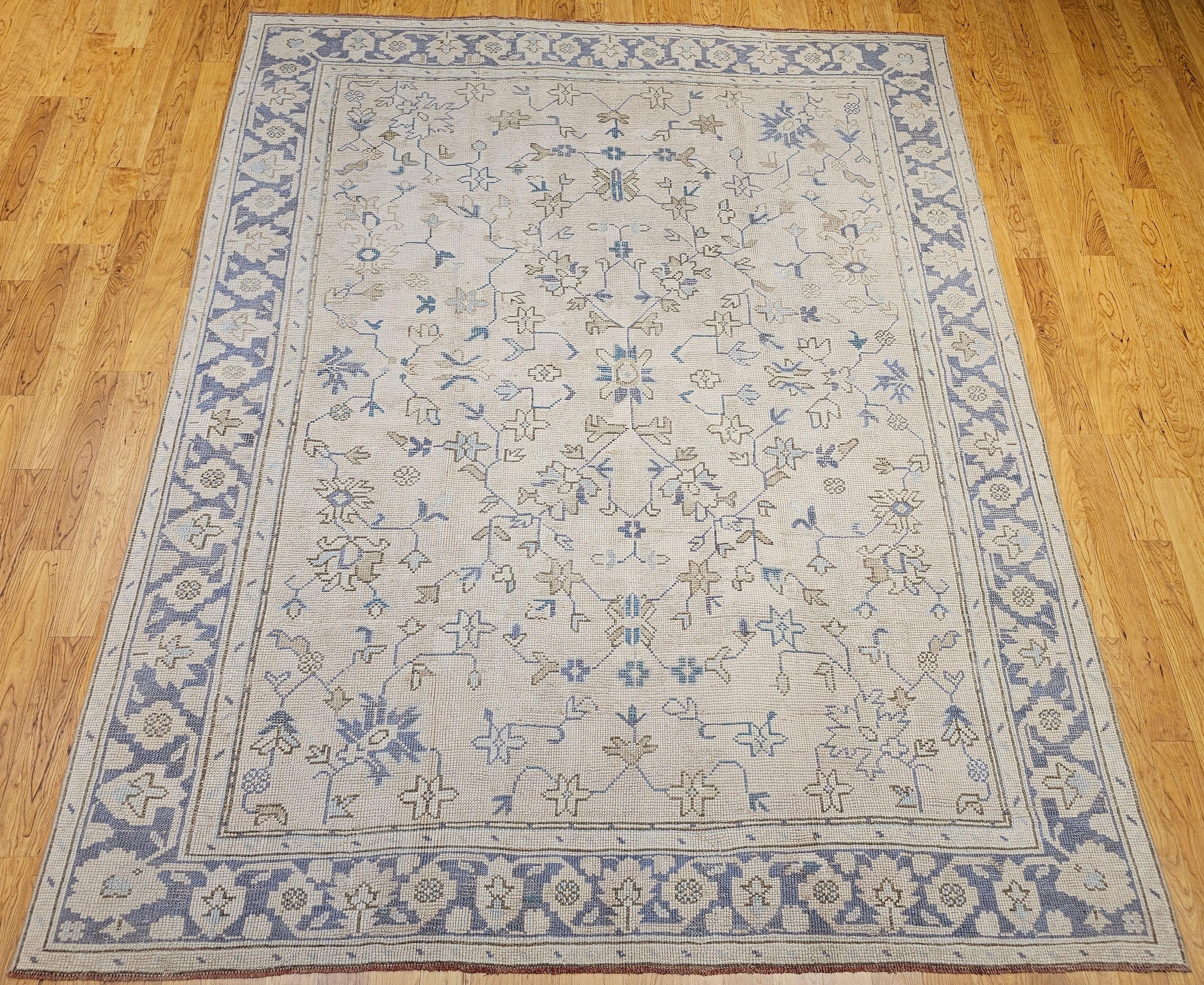 Tappeto vintage Oushak turco annodato a mano con motivo allover nei colori avorio, marrone, blu e lavanda della metà del 1900.  Questo bellissimo tappeto turco presenta un disegno geometrico di grandi dimensioni su uno sfondo color avorio e con