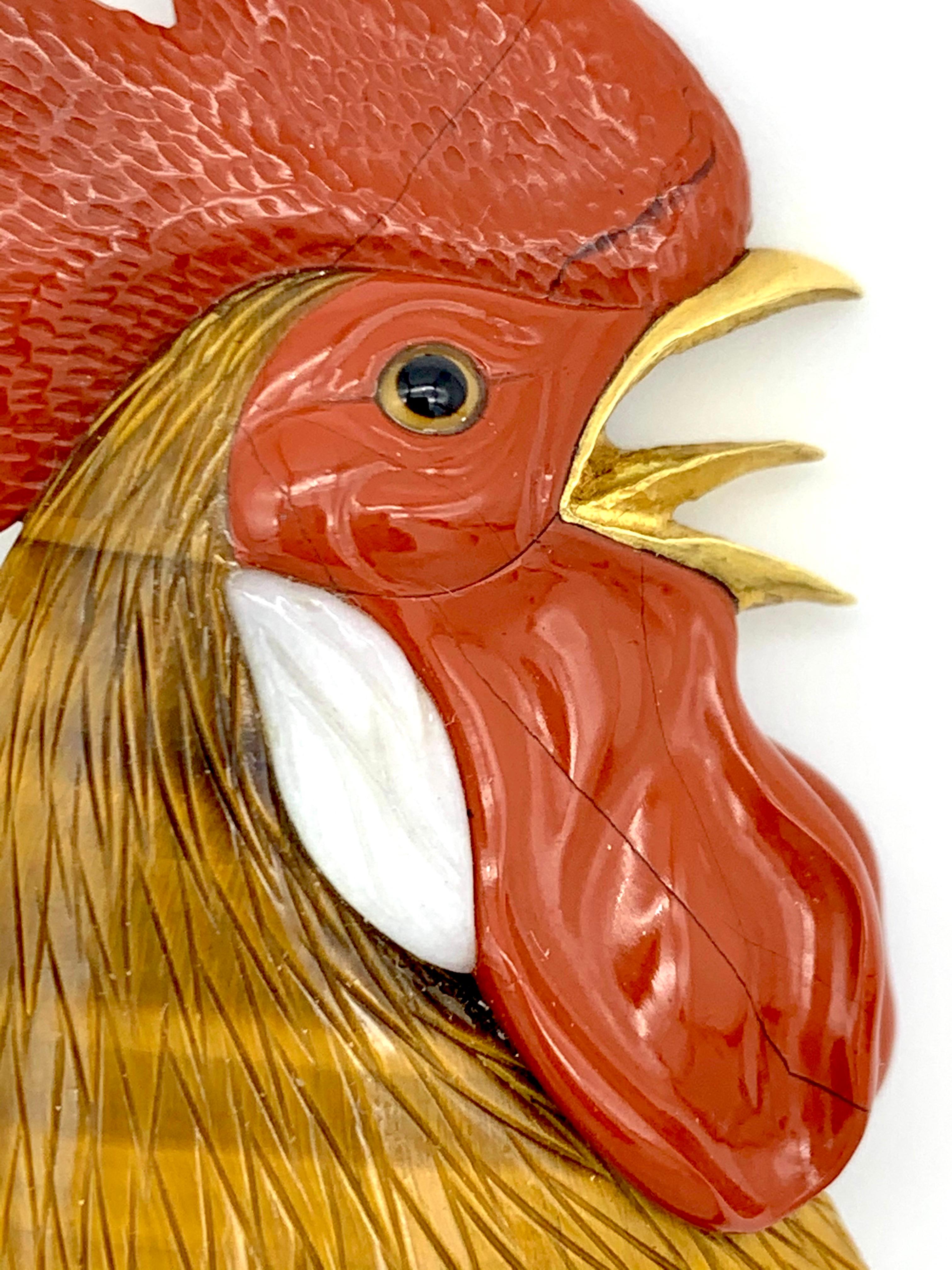 Cette superbe tête de coq a été sculptée dans de l'œil de tigre et diverses pierres dures. Le bec et la monture de la broche sont exécutés en or 18 carats.