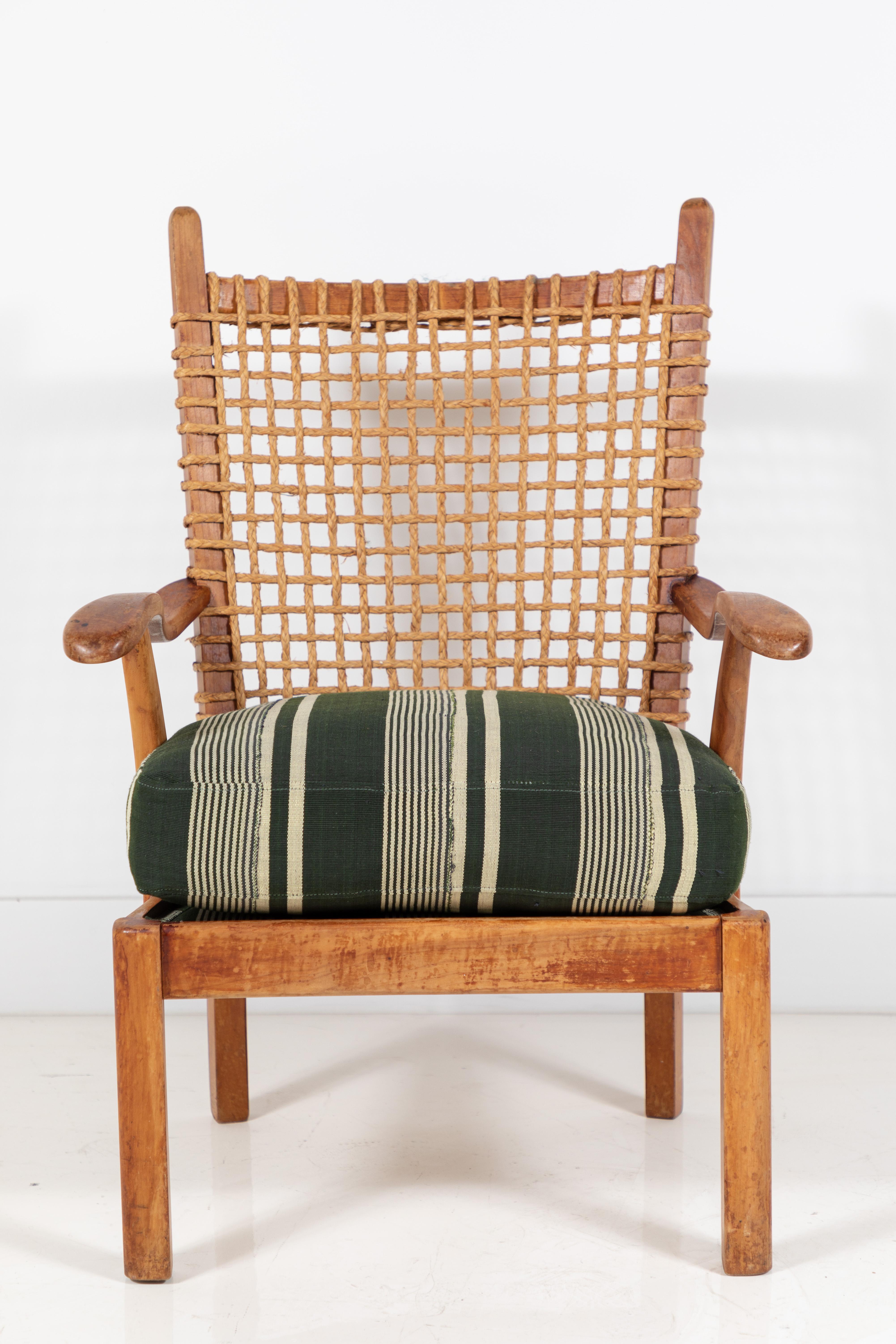 Vintage wooden arm chair with back rest made of woven rope, newly upholstered green striped seat cushion made from a one of a kind African textile.