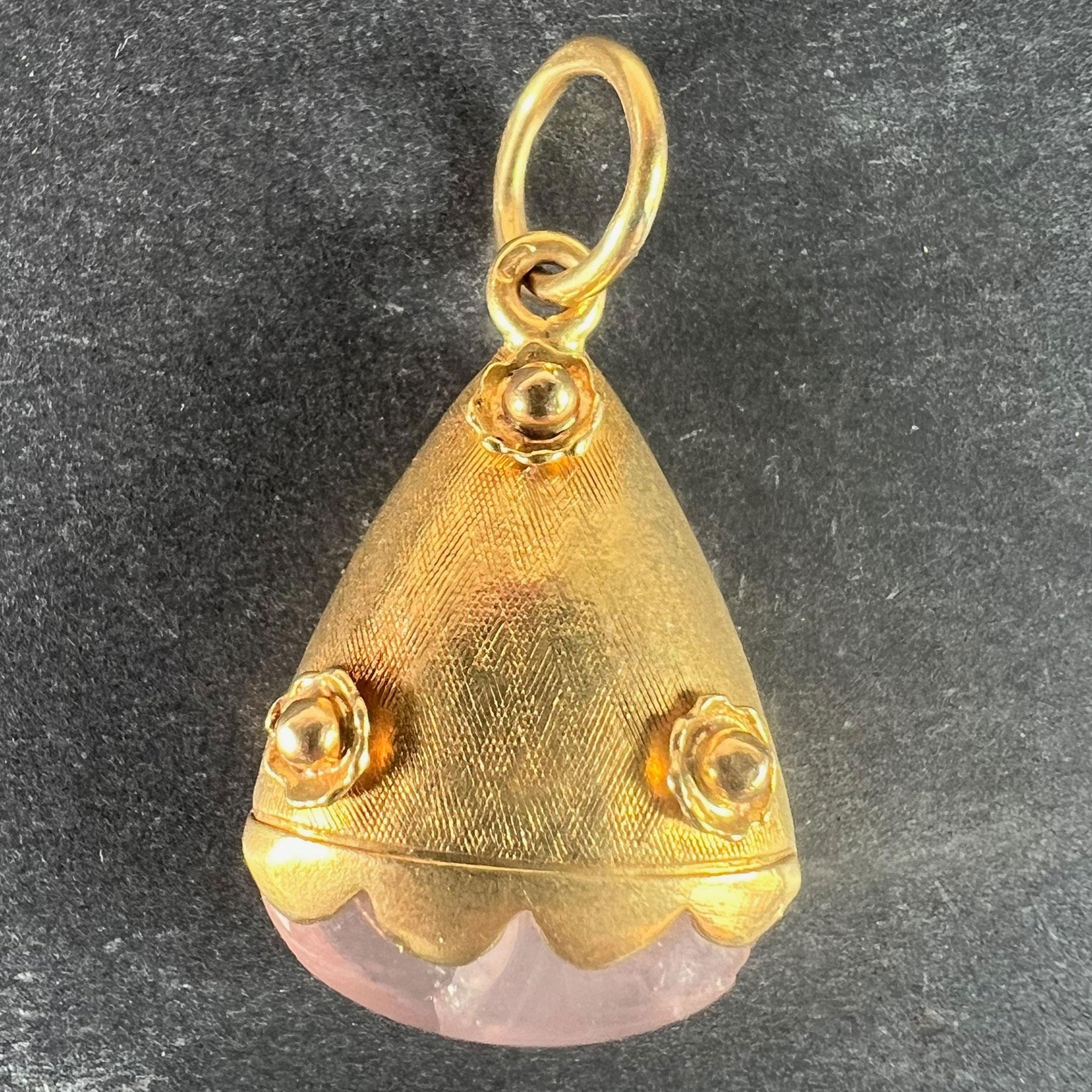 A vintage 18 karat (18K) yellow gold charm pendant designed as a flaring oval cylinder with cross-hatch and rosette flowers decoration, mounted to the base with an oval rose quartz cabochon (fractured). Stamped with the owl mark for French import