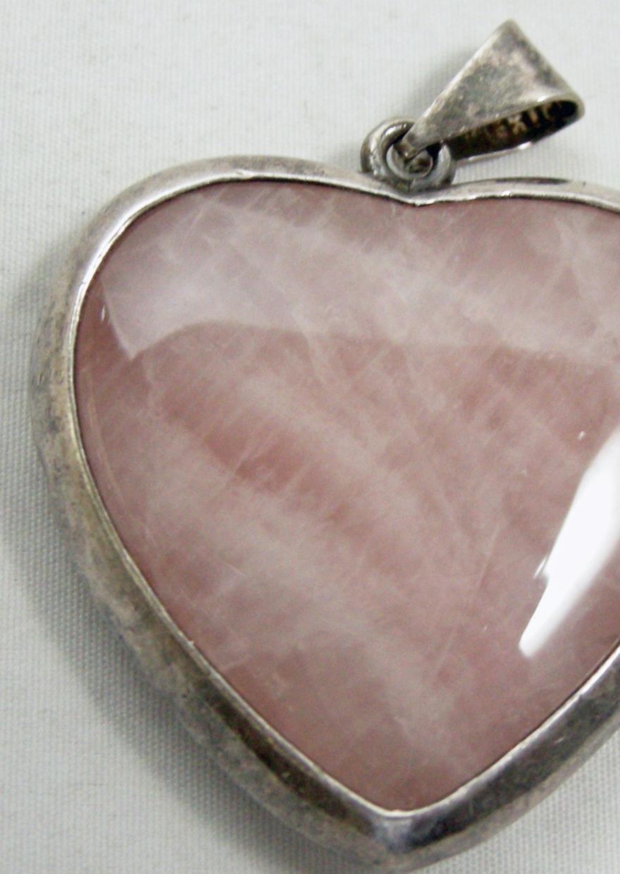 This vintage heart pendant is made with rose quartz in the center in a sterling silver frame. In excellent condition, this pendant measures 2” x 1-5/8”.
