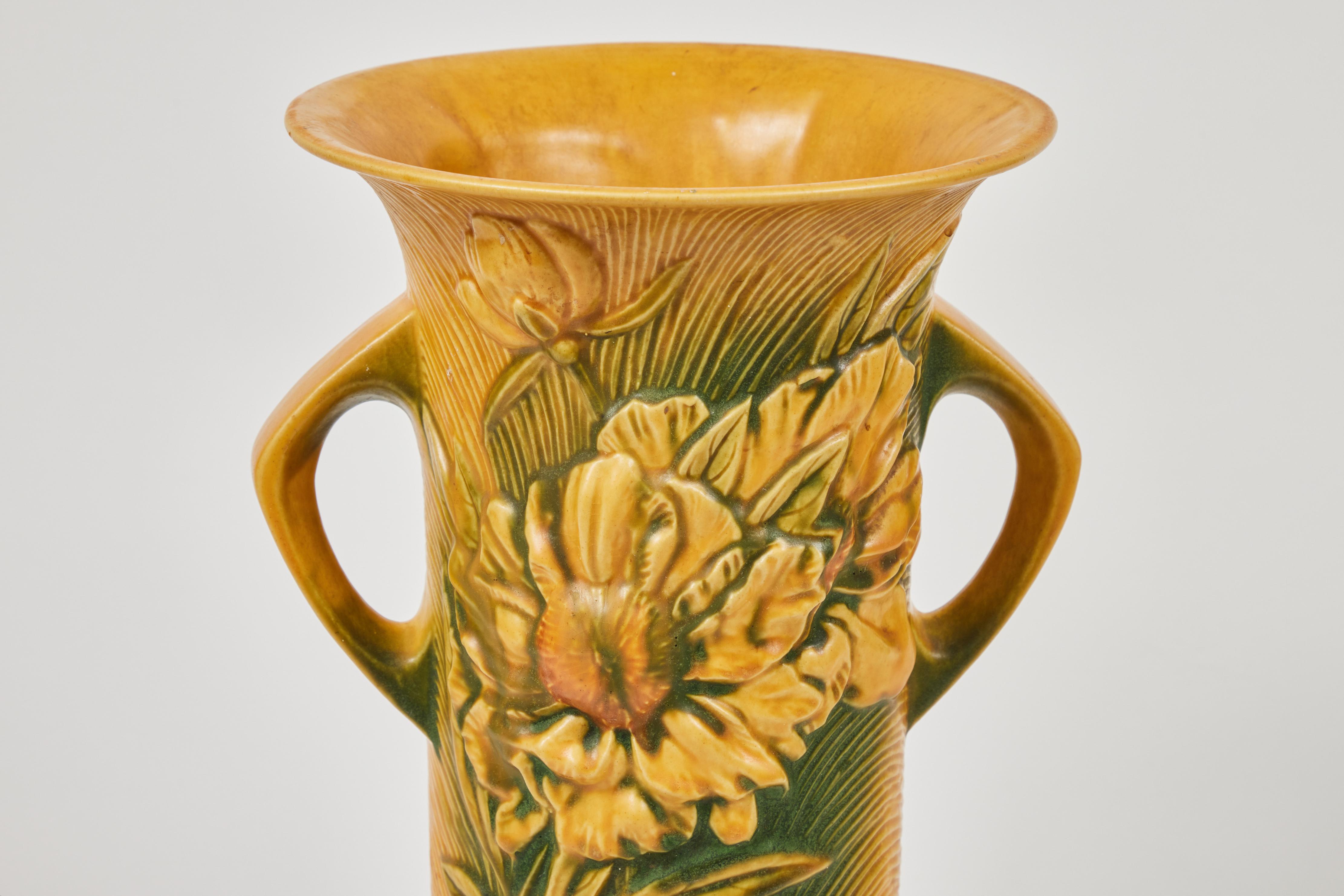 Fantastic large vintage Roseville pottery peony vase is double handled and embossed on both sides with 2 open blooming peony flowers. It is yellow and green glazed. Made in the USA and circa 1940's, this vase has the marking 9-15 on the bottom.

 